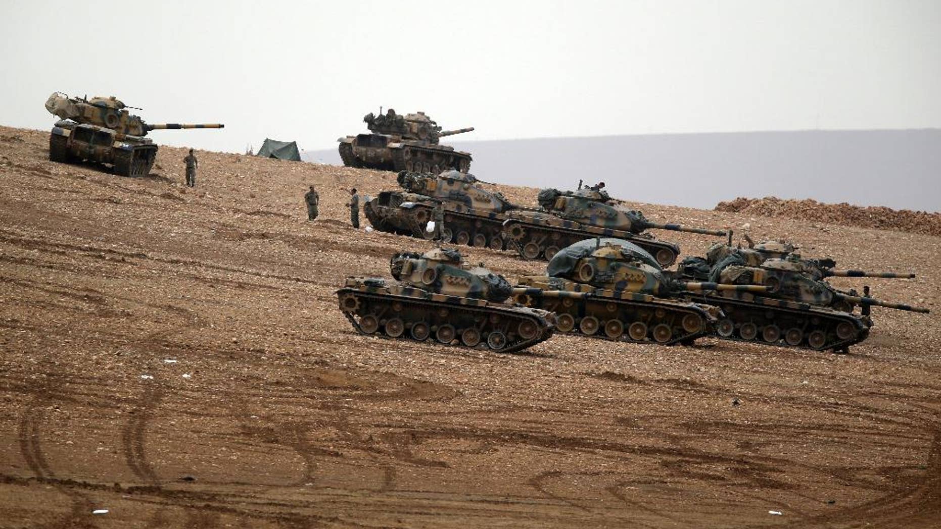 Turkish soldiers hold their positions with their tanks on a hilltop on the outskirts of Suruc, at the Turkey-Syria border, overlooking Kobani, Syria, during fighting between Syrian Kurds and the militants of Islamic State group, Sunday, Oct. 12, 2014. Kobani, also known as Ayn Arab, and its surrounding areas, has been under assault by extremists of the Islamic State group since mid-September and is being defended by Kurdish fighters.(AP Photo/Lefteris Pitarakis)