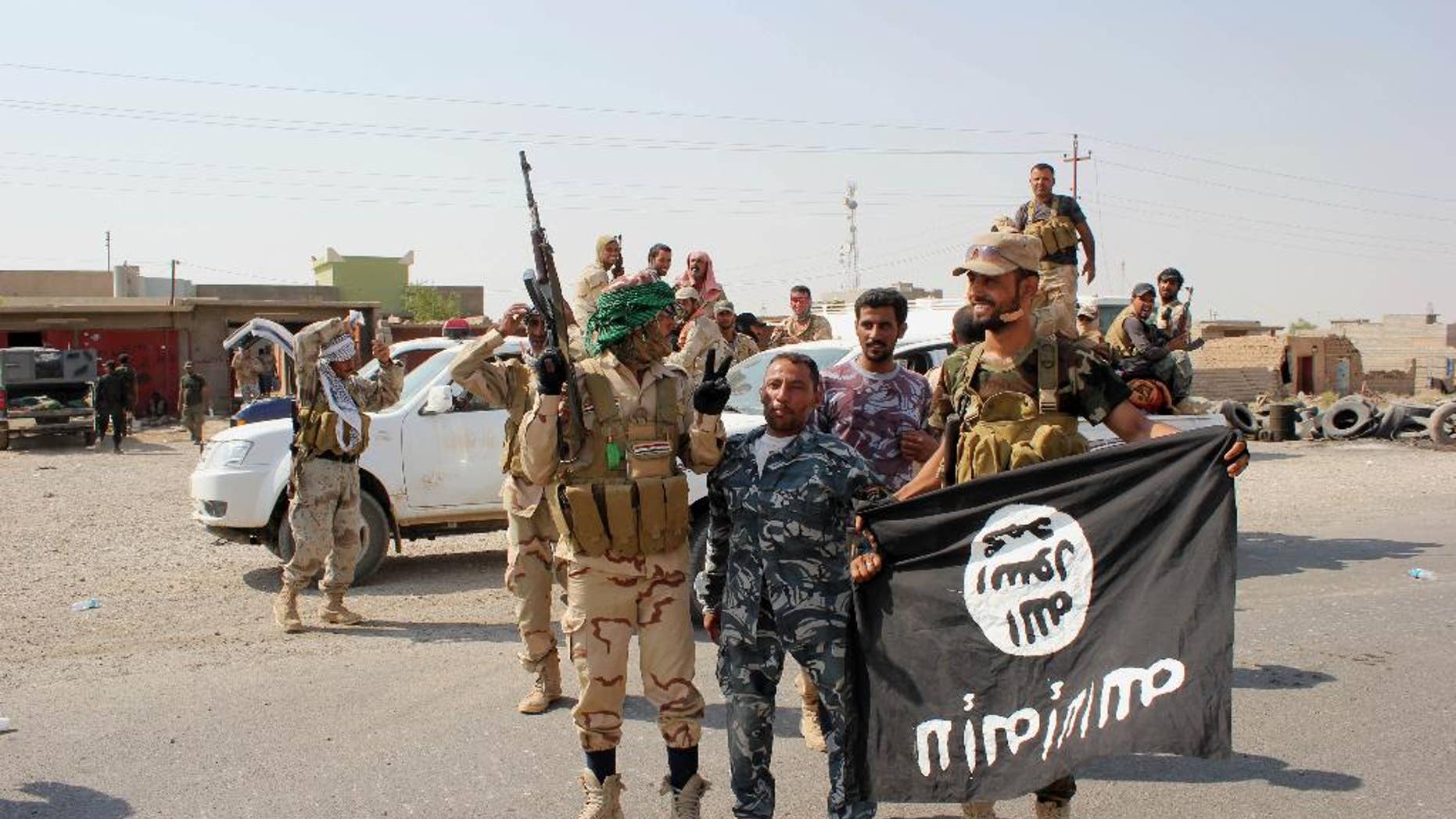 In this Monday, Sept. 1, 2014 photo, Shiite militiamen hold the flag of the Islamic State group they captured, during an operation outside Amirli, some 105 miles (170 kilometers) north of Baghdad, Iraq. Under the shadow of the Islamic State group threat, governments from France to Indonesia are moving aggressively to block would-be jihadis from taking their fight to Syria and Iraq. New laws make it easier to seize passports. Suspected fighters are being plucked from planes. Authorities are blocking finances and shutting down radical mosques. Behind the scenes, Western intelligence agencies are striving to stay ahead of tech-savvy radicalized Muslims by pressuring Silicon Valley firms to wipe extremist content from websites and toying with new technologies to identify returning fighters at the border. Britain has taken a particularly active role in censoring content deemed to break the country’s strict rules against extremist propaganda. U.K. officials recently revealed it had been granted “super flagger” status on sites such as YouTube, meaning their requests to remove videos with grisly content or that encourage terrorism are fast-tracked. (AP Photo)