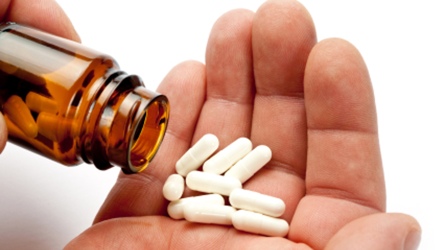 taking drugs. Open glass container and some pills in male hand.