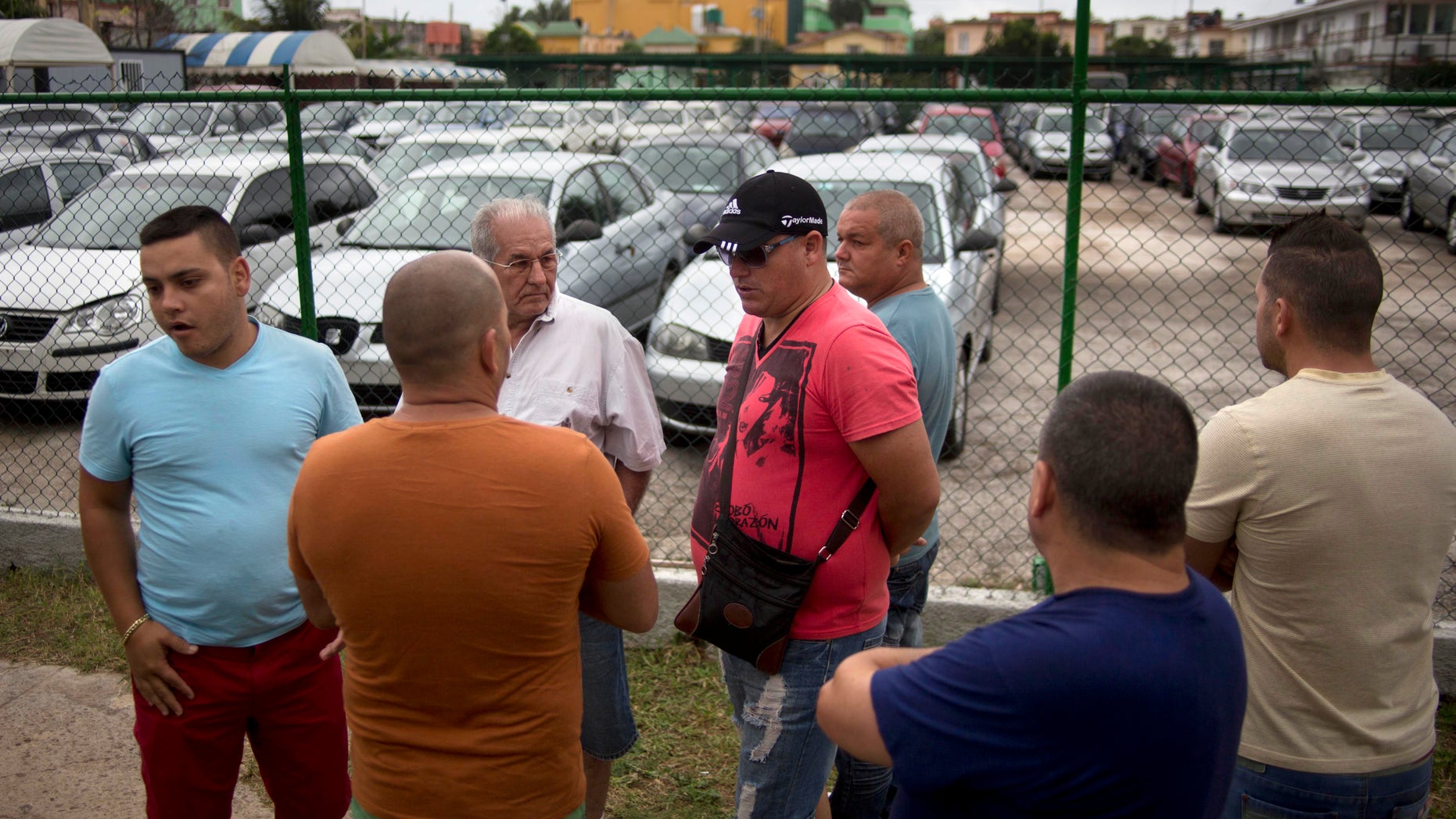 People gather outside a government-run car dealership that sells used vehicles in Havana, Cuba, Friday, Jan. 3, 2014. Cubans are eagerly visiting car dealerships as a new law takes effect on Friday eliminating a special permit requirement that has greatly restricted vehicle ownership in the country. To their dismay they found sharply hiked prices on the first day the law was in force. In Cuba, the government retains its monopoly on a vehicle's market value. (AP Photo/Ramon Espinosa)