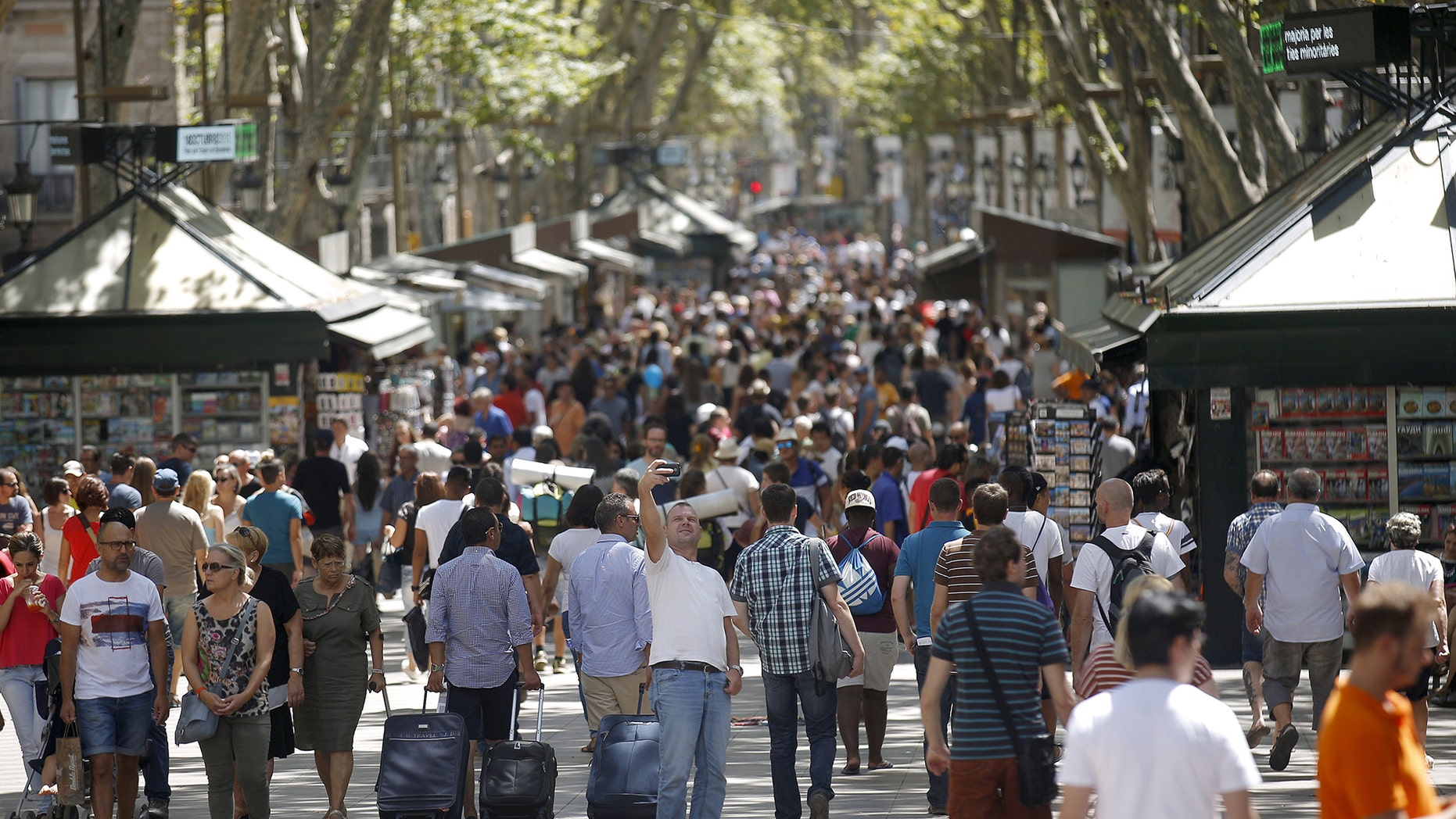 A man takes a selfie at Las Ramblas in Barcelona, Spain, August 16, 2015. Barcelona's new mayor is picking a fight with home rental websites as she tries to crack down on uncontrolled tourism that she fears could drive out poor residents and spoil the Catalan capital's charm. Picture taken on August 16, 2015. REUTERS/Albert Gea - RTX1PQRT