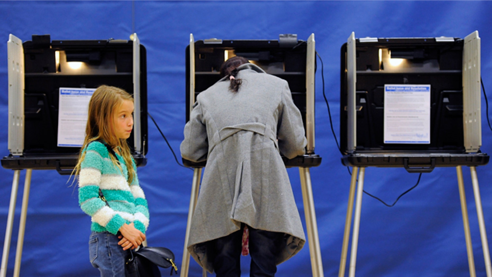 Nov. 4, 2014: Alice Kunde, 8, left, waits for her mother Laura Kunde to vote at the Barnum Recreation Center in Denver.