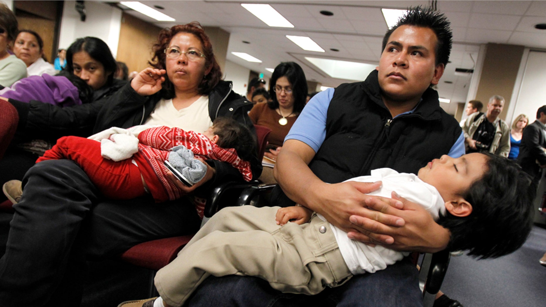 Marko Garduno, top right, holds a sleeping Dillon Garduno, 2 1/2, as they join dozens of others as they listen to Arizona lawmakers give their first hearing to a bill that challenges automatic U.S. citizenship for children of illegal immigrants, the state's latest foray into the national debate over illegal immigration at the Arizona Capitol, Monday, Feb. 7, 2011, in Phoenix. The bill to be heard Monday by the Senate judiciary committee seeks a court interpretation on an element of the 14th Amendment, which guarantees citizenship to people born in the U.S. who are "subject to the jurisdiction" of this country. (AP Photo/Ross D. Franklin)