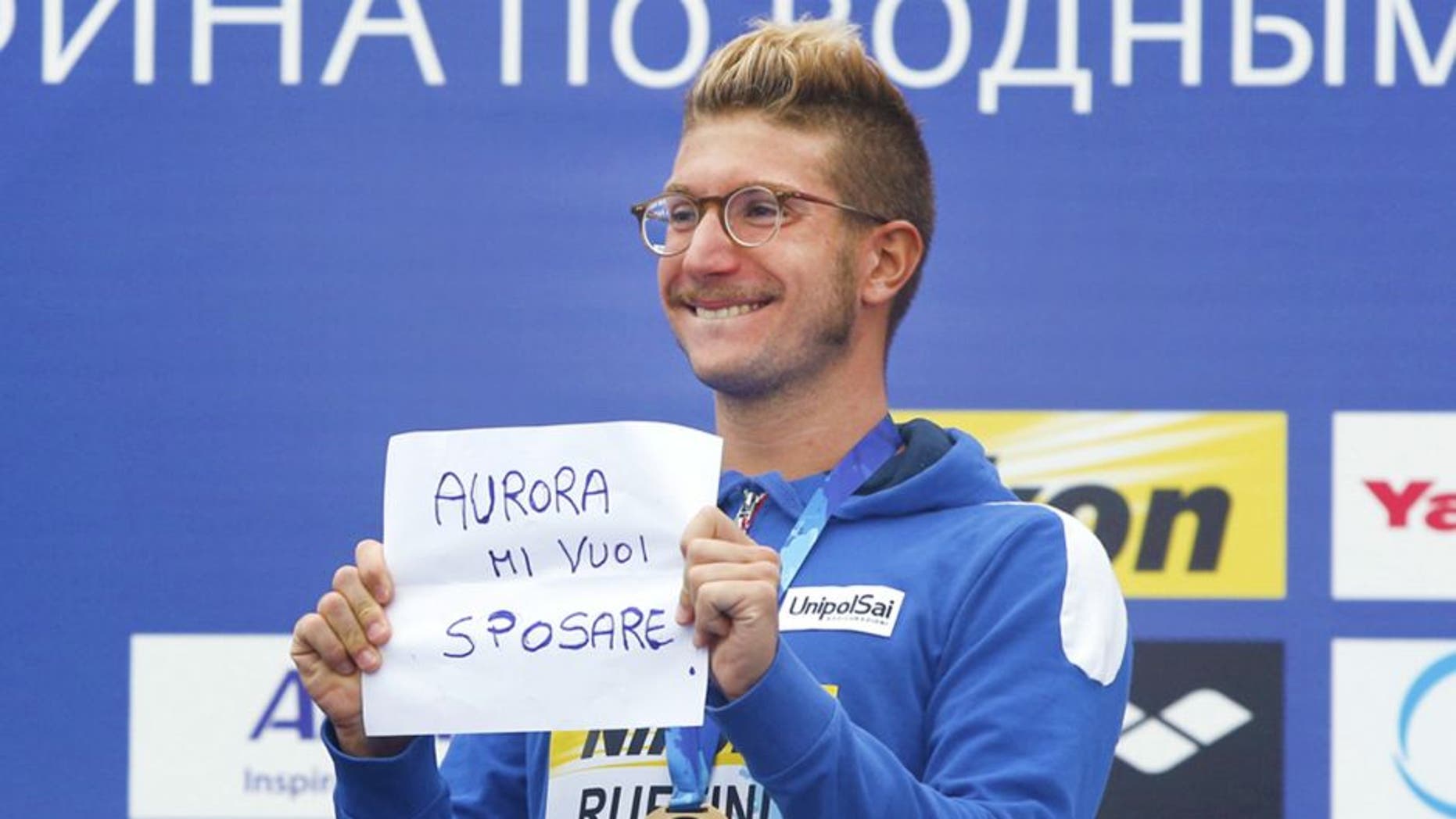 Italy's gold medal winner Simone Ruffini shows a placard "Aurora, you want to marry me" during the ceremony for the men's 25km open water swim competition at the Swimming World Championships in Kazan, Russia, Saturday, Aug. 1, 2015. (AP Photo/Sergei Grits)
