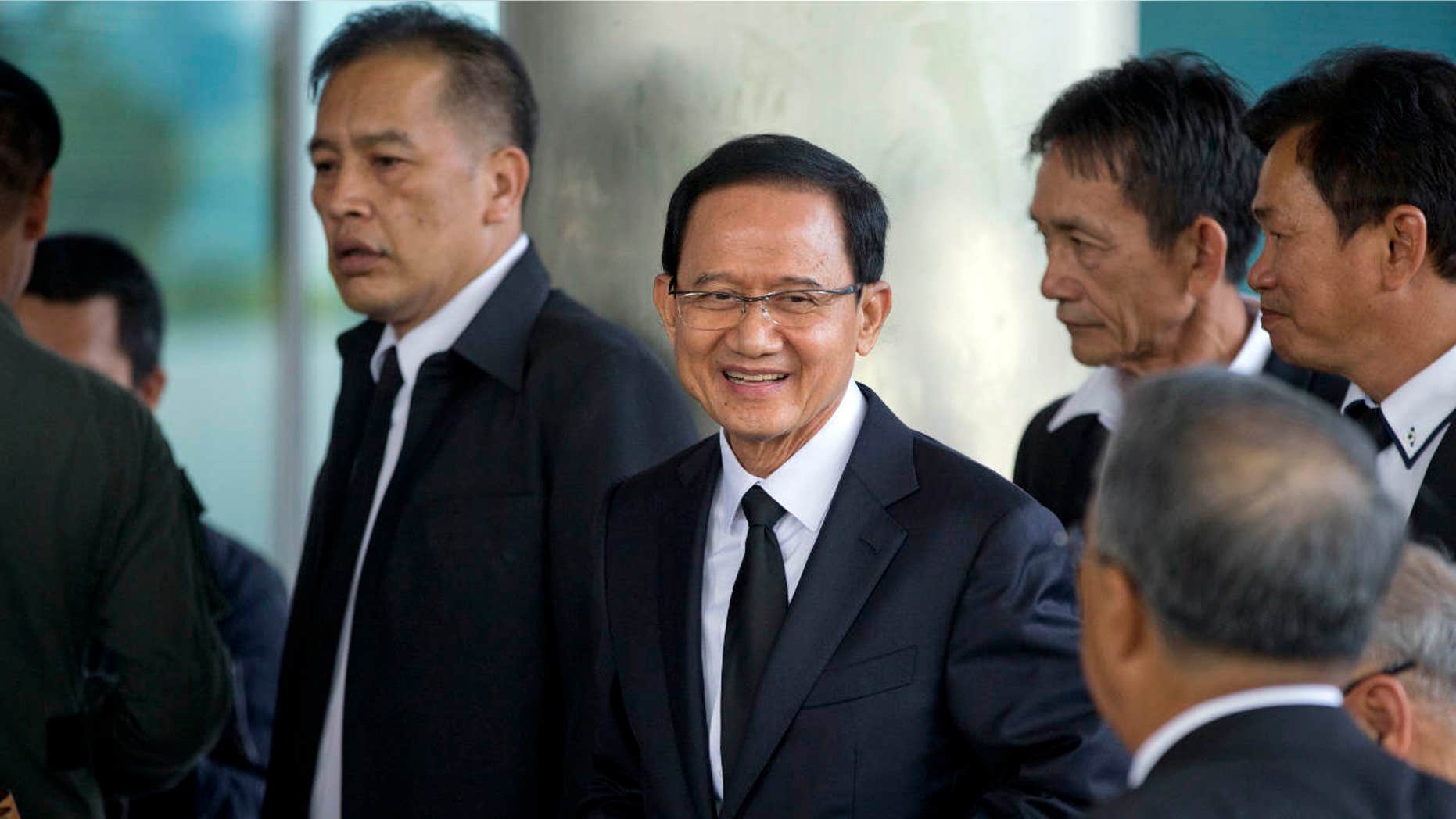 Thailand's former Prime Minister Somchai Wongsawat, center, smilies upon his arrival at a courthouse Wednesday, Aug. 2, 2017, in Bangkok, Thailand.