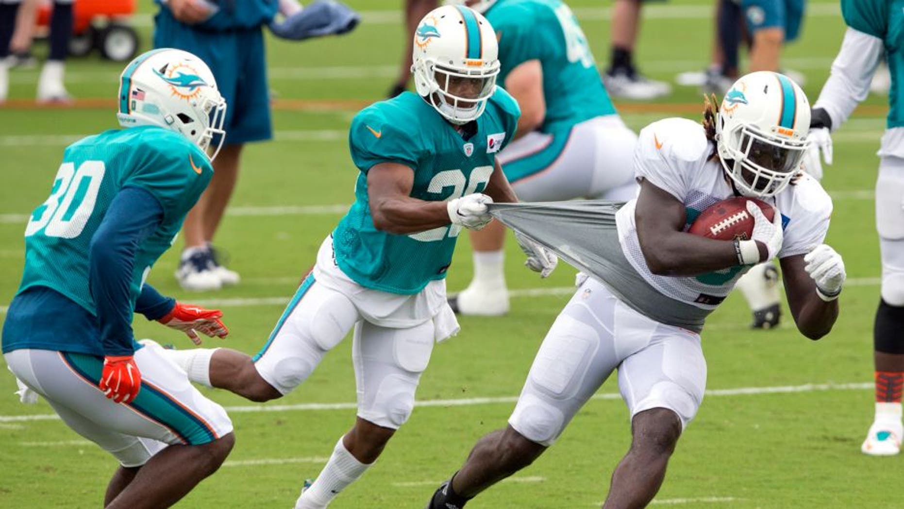 Miami Dolphins cornerback Bobby McCain (28) attempts to slow down Miami Dolphins running back Jay Ajayi (33) during NFL training camp, Saturday, Aug. 1, 2015 at Nova Southeastern University in Davie, Fla. (Al Diaz/The Miami Herald via AP) MAGS OUT; MANDATORY CREDIT