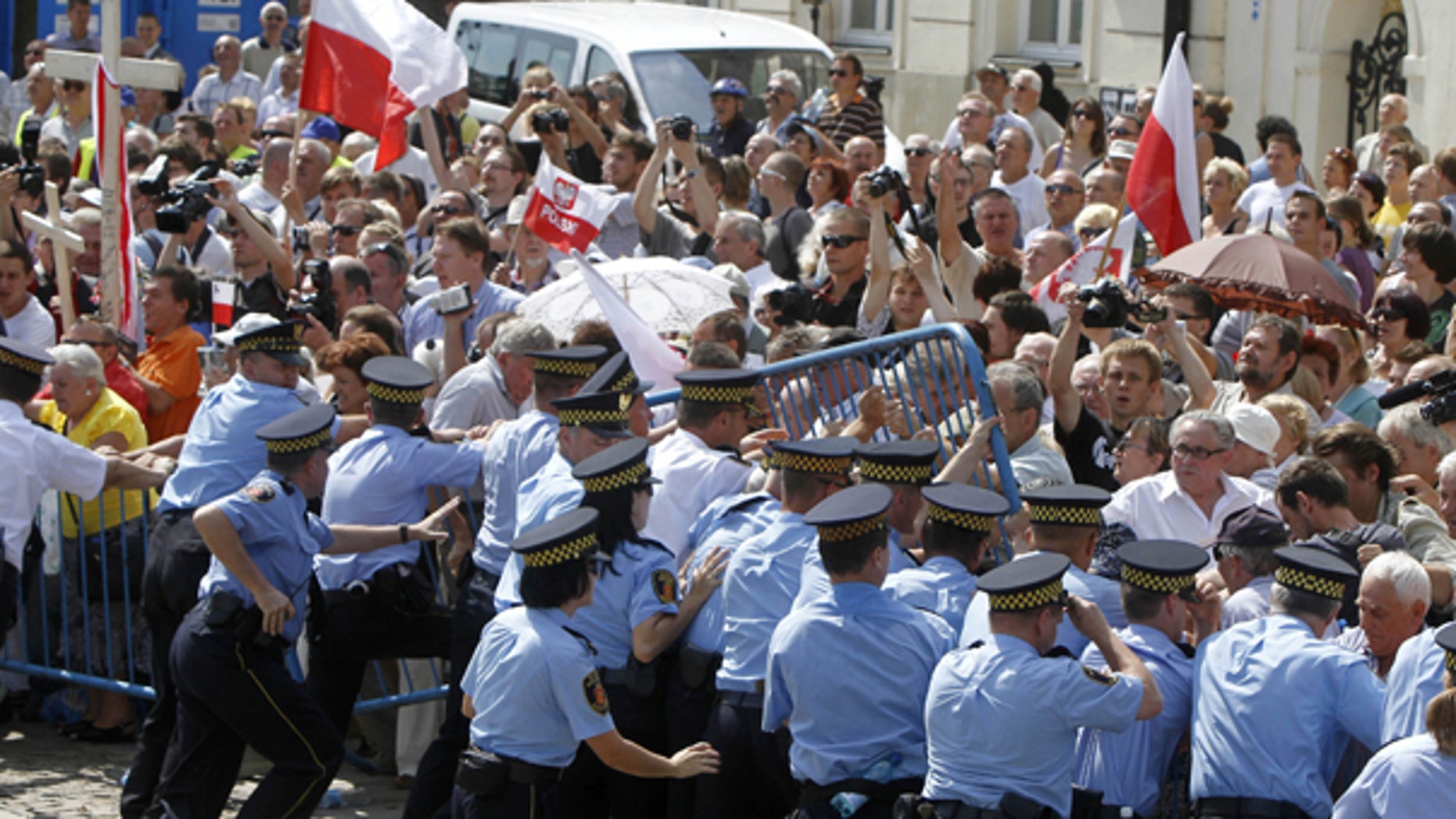 Aug. 3: Supporters of late Polish President Lech Kaczynski scuffle with municipal guards as they try to break a barrier in front of the Presidential palace in Warsaw. Authorities failed to move a cross commemorating Poland's late leader Lech Kaczynski from in front of the presidential palace after fierce protests by Roman Catholic groups and Kaczynski's followers.