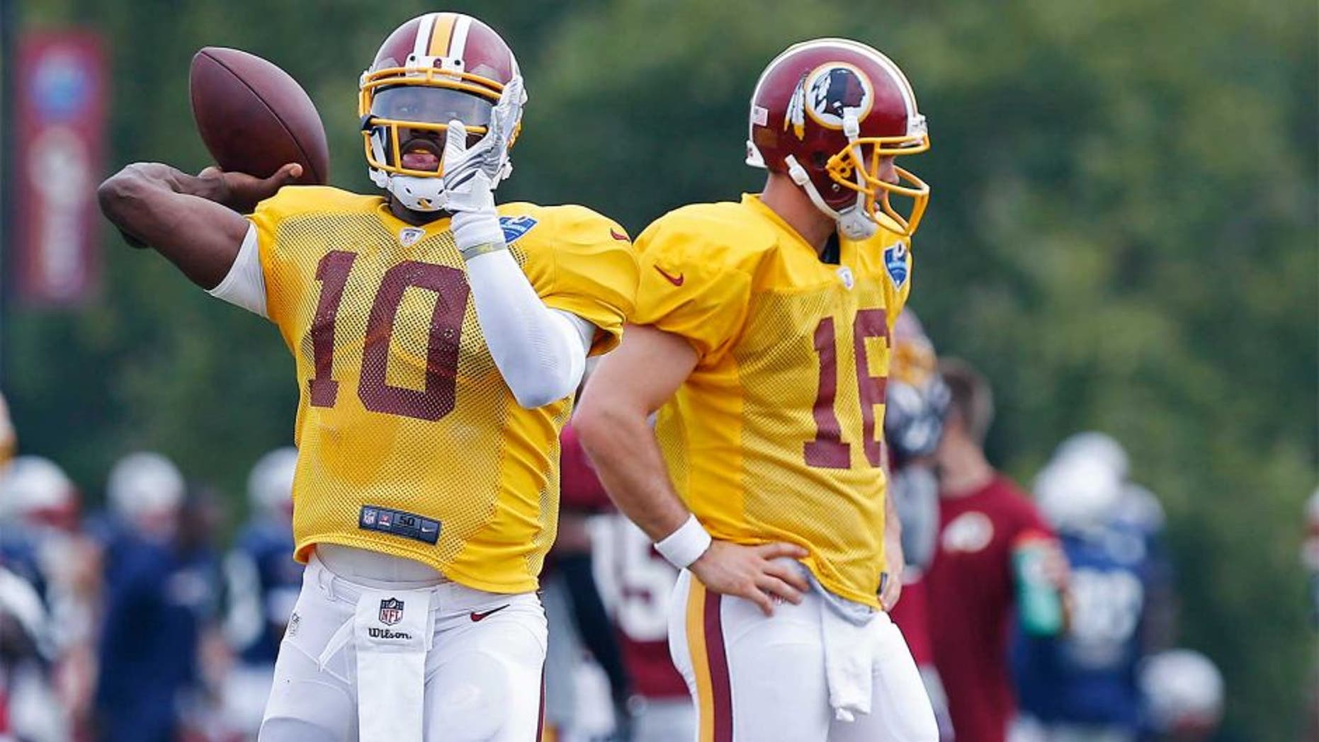 Aug 4, 2014; Richmond, VA, USA; Washington Redskins quarterback Robert Griffin III (10) throws the ball as Redskins quarterback Colt McCoy (16) looks on during joint practice with the New England Patriots on day ten of training camp at the Bon Secours Washington Redskins Training Center. Mandatory Credit: Geoff Burke-USA TODAY Sports