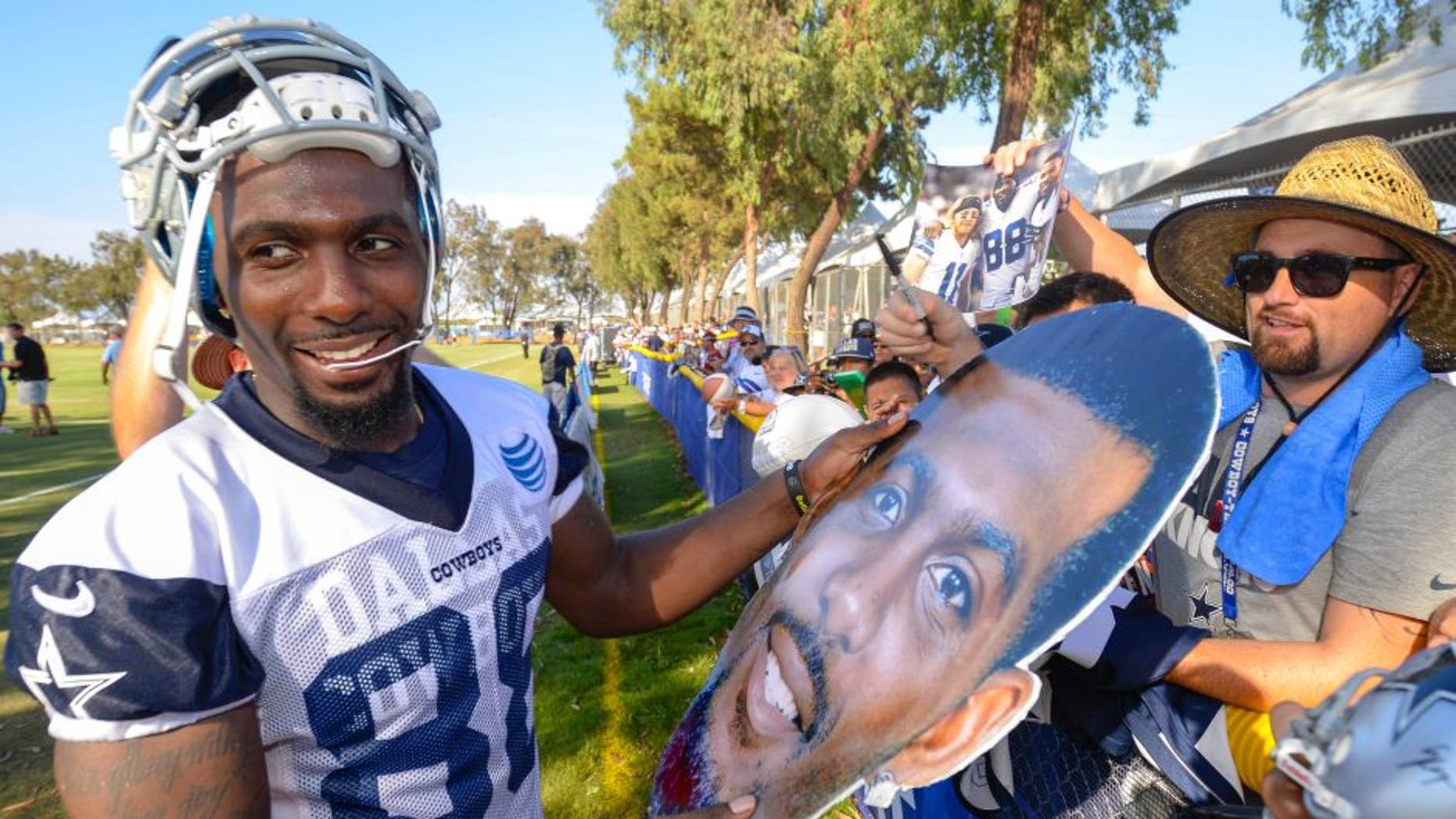 Dallas Cowboys wide receiver Dez Bryant is handed a large cutout photo of his head to sign after afternoon practice during NFL football training camp, Friday, July 31, 2015, in Oxnard, Calif. (AP Photo/Gus Ruelas)