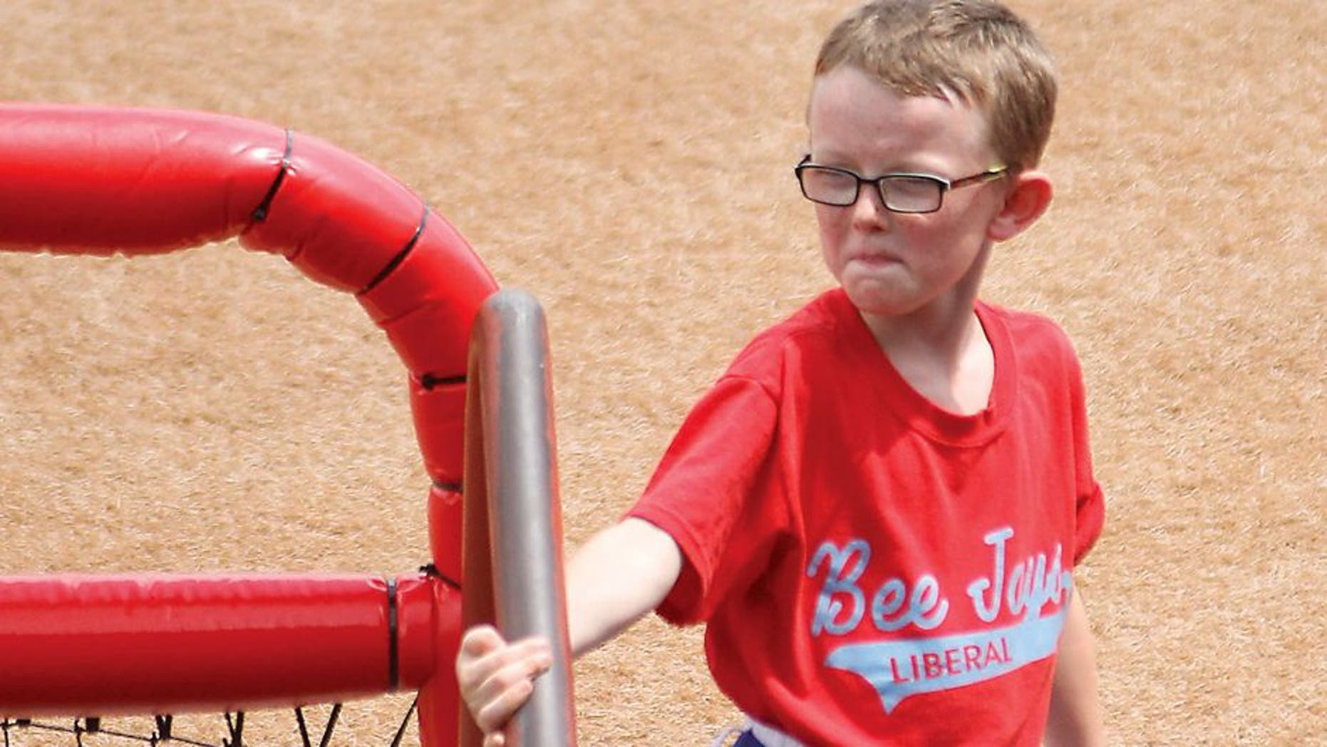 In this Aug. 1, 2015, photo, bat boy Kaiser Carlile, 9, gets ready for a National Baseball Congress World Series baseball game between the Liberal Bee Jays and San?Diego Waves outside the dugout in Wichita, Kan. Kaiser, who was wearing a helmet, was accidentally hit in the head during the game by a follow-through swing near the on-deck circle. He died on Sunday. (Earl Watt/Leader & Times via AP) MANDATORY CREDIT