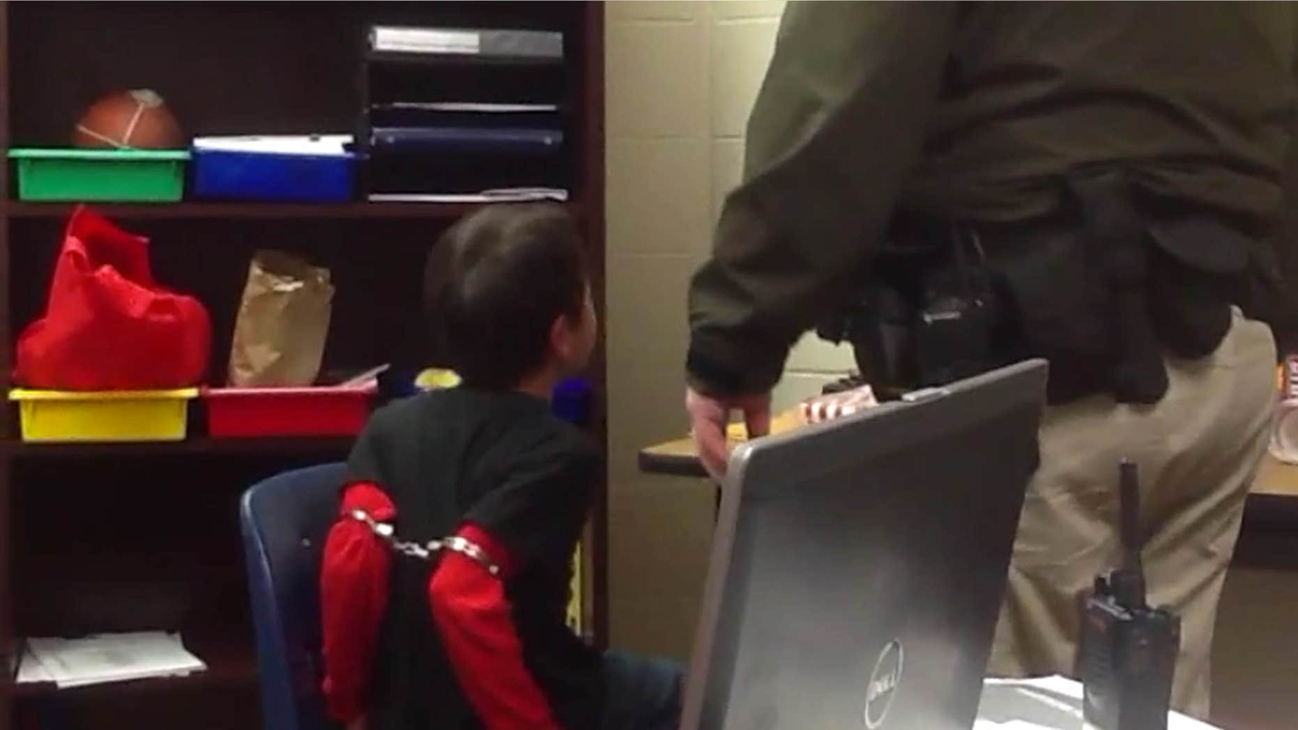Aug. 4, 2015: In this image made from video taken in August 2014, and provided by the American Civil Liberties Union, an 8-year-old boy struggles and cries out as he sits in a chair with handcuffs around his biceps and his arms locked behind him while a school resource officer stands nearby, at an elementary school in Covington, Ky.