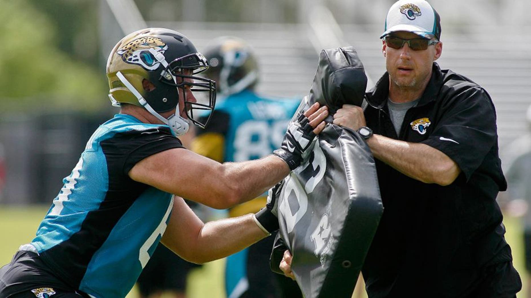 May 28, 2015; Jacksonville, FL, USA; Jacksonville Jaguars center Stefen Wisniewski (61) hits the blocking pad held by strength and conditioning coordinator Tom Myslinski during OTAs at the Florida Blue Health and Wellness Practice Fields. Mandatory Credit: Phil Sears-USA TODAY Sports