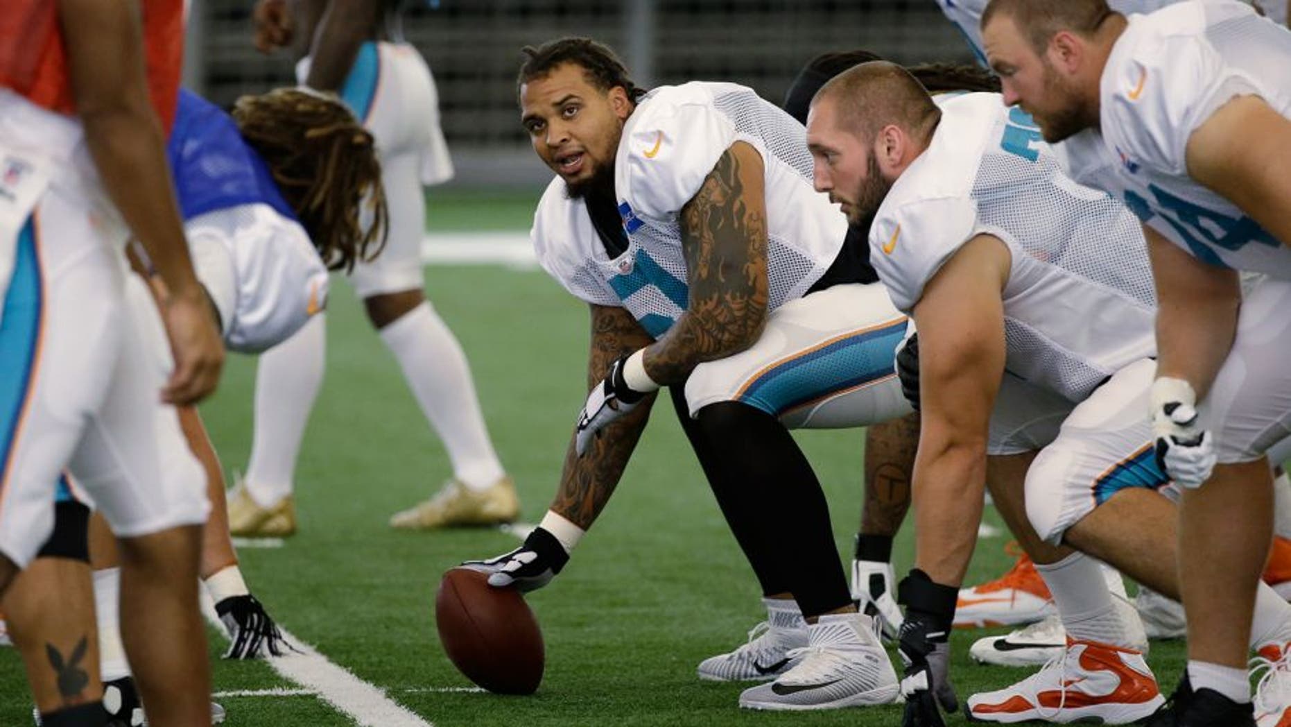 Miami Dolphins center Mike Pouncey, center, prepares to snap the ball at the teams NFL football training camp, Wednesday, Aug. 5, 2015, in Davie, Fla. (AP Photo/Wilfredo Lee)