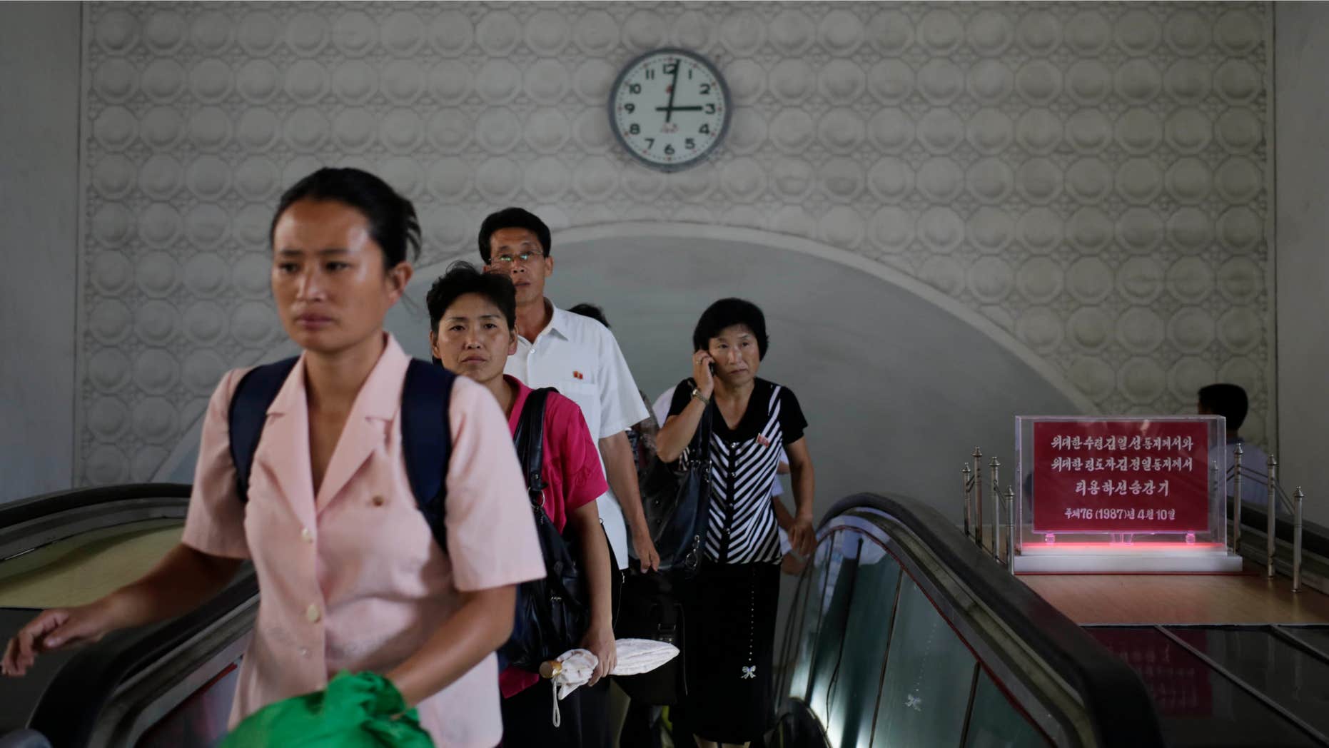 Sept. 1, 2014: A clock hangs on the wall as North Koreans leave an underground train station in Pyongyang, North Korea.