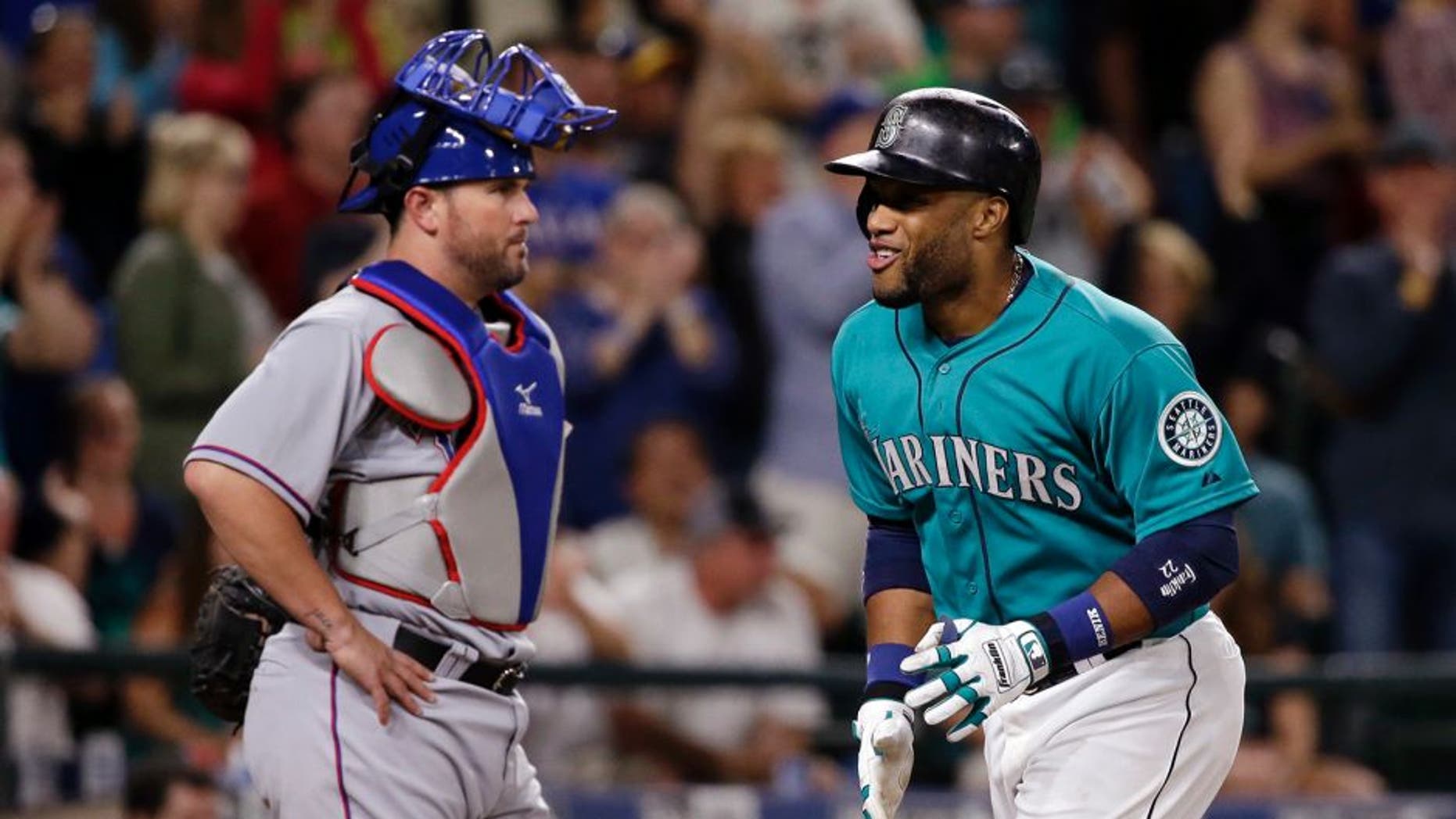 Seattle Mariners' Robinson Cano, right, smiles as he scores on his home run as Texas Rangers catcher Bobby Wilson waits during the sixth inning of a baseball game Friday, Aug. 7, 2015, in Seattle. (AP Photo/Elaine Thompson)