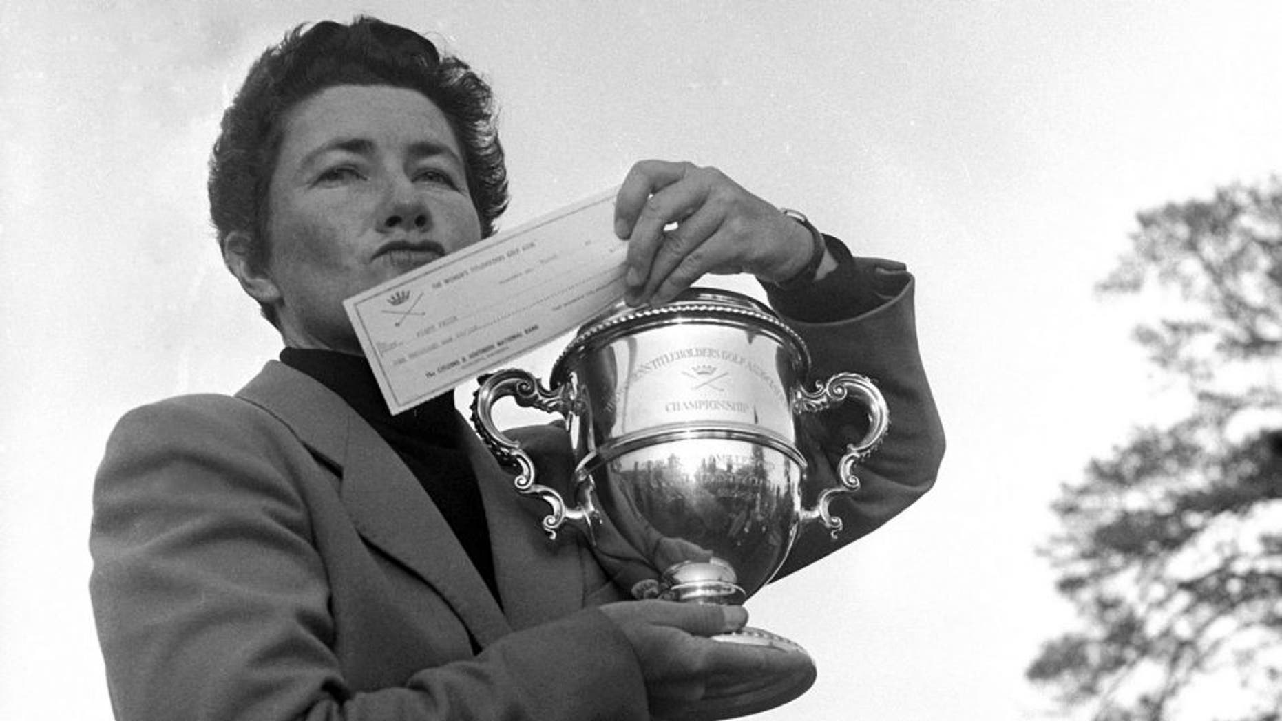 FILE - In this March 15, 1959 file photo, Louise Suggs of Atlanta, Ga., holds up the winner's cup and a check for $1,000 after winning the Women's Titleholders golf championship in Augusta, Ga. The LPGA Tour says Suggs, an LPGA founder and one of the greatest female golfers of all time, died Friday, Aug. 7, 2015, in Sarasota, Fla. She was 91. The LPGA did not list a cause of death. (AP Photo/Horace Cort, File)
