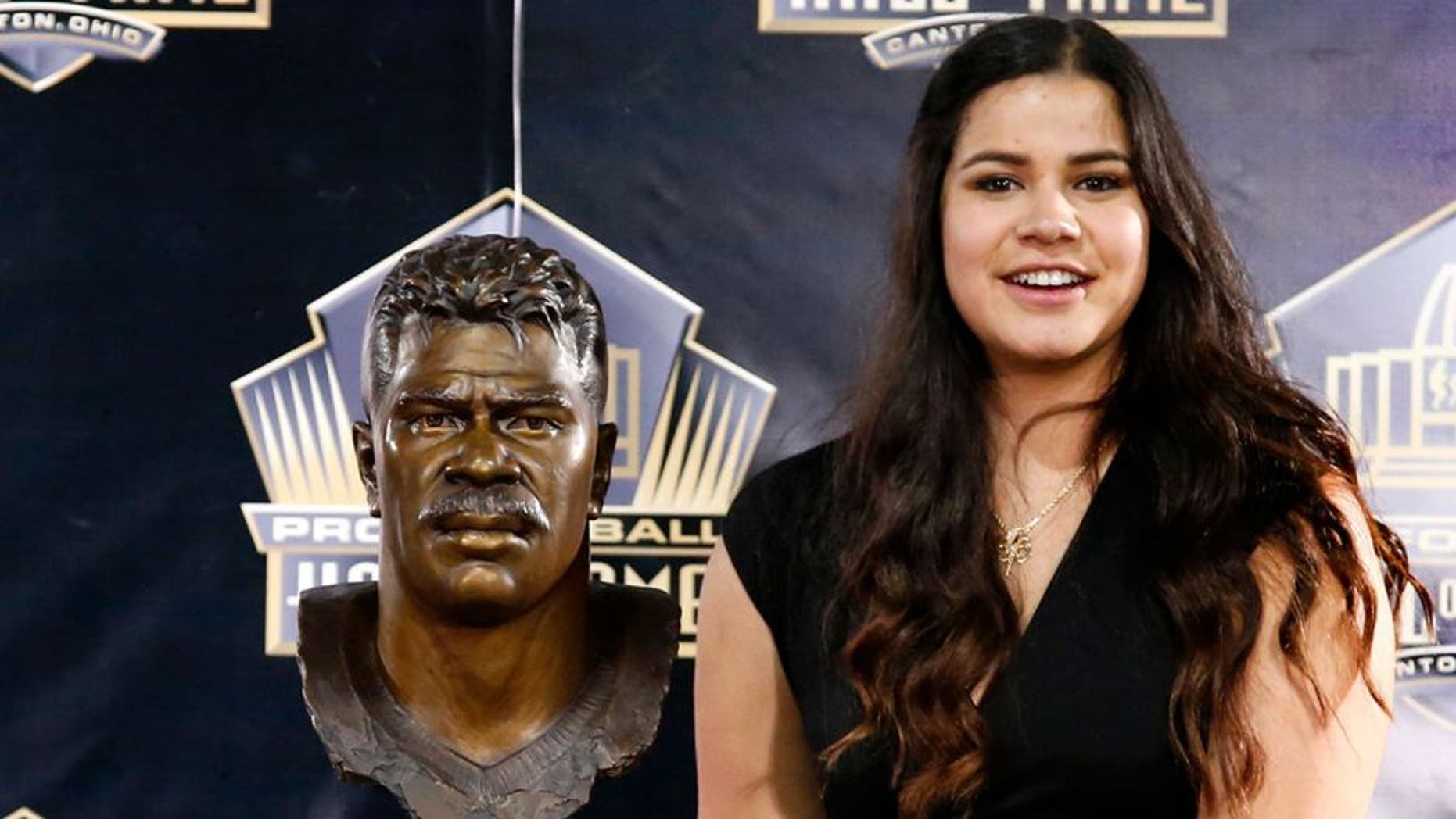 Sydney Seau, aughter of former NFL player Junior Seau, poses with a bust of her father during inductions at the Pro Football Hall of Fame Saturday, Aug. 8, 2015, in Canton, Ohio. (AP Photo/Gene J. Puskar)