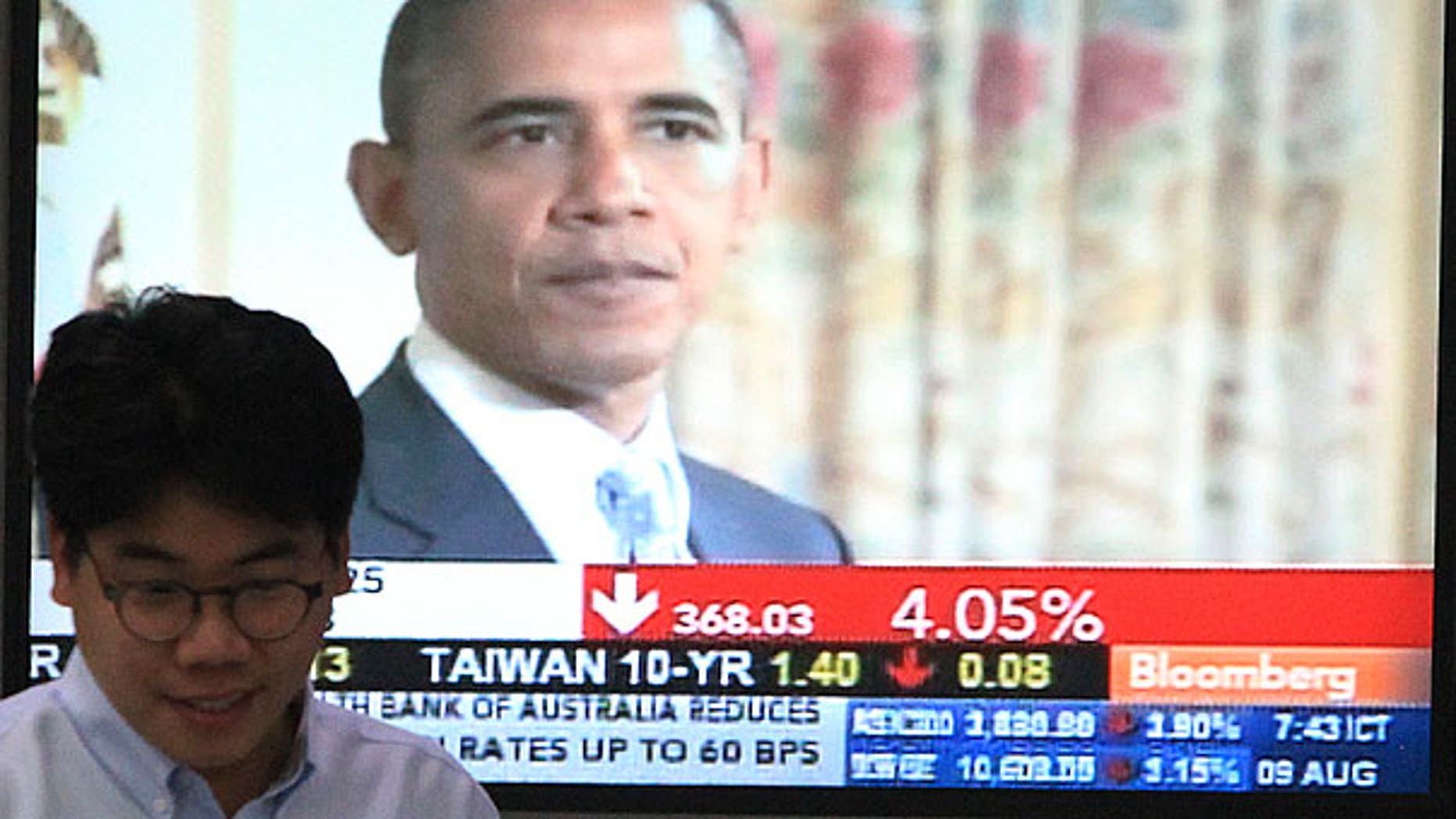 Aug. 9: A currency trader works in front of a TV showing U.S. President Barack Obama at the Korea Exchange Bank headquarters in Seoul, South Korea.
