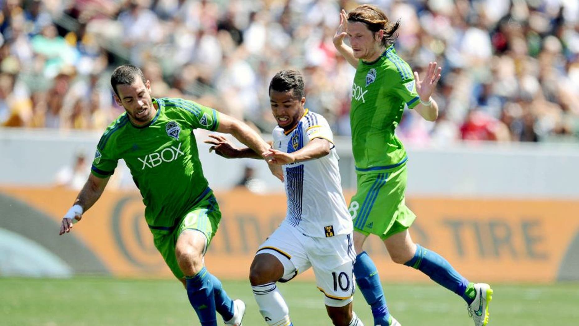 August 9, 2015; Carson, CA, USA; Los Angeles Galaxy midfielder/forward Giovani Dos Santos (10) moves the ball against Seattle Sounders defender Zach Scott (20) and midfielder Erik Friberg (28) during the first half at StubHub Center. Mandatory Credit: Gary A. Vasquez-USA TODAY Sports
