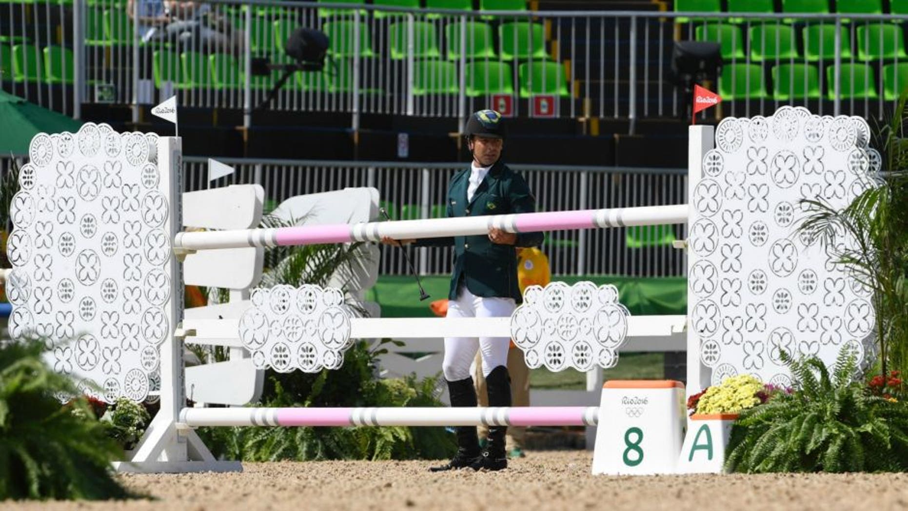 Brazil's Ruy Fonseca replaces the bar after he fell from his horse Tom Bombadill Too while competing during the Eventing's Individual Jumping of the Equestrian during the 2016 Rio Olympic Games at the Olympic Equestrian Centre in Rio on August 9, 2016. / AFP / John MACDOUGALL (Photo credit should read JOHN MACDOUGALL/AFP/Getty Images)