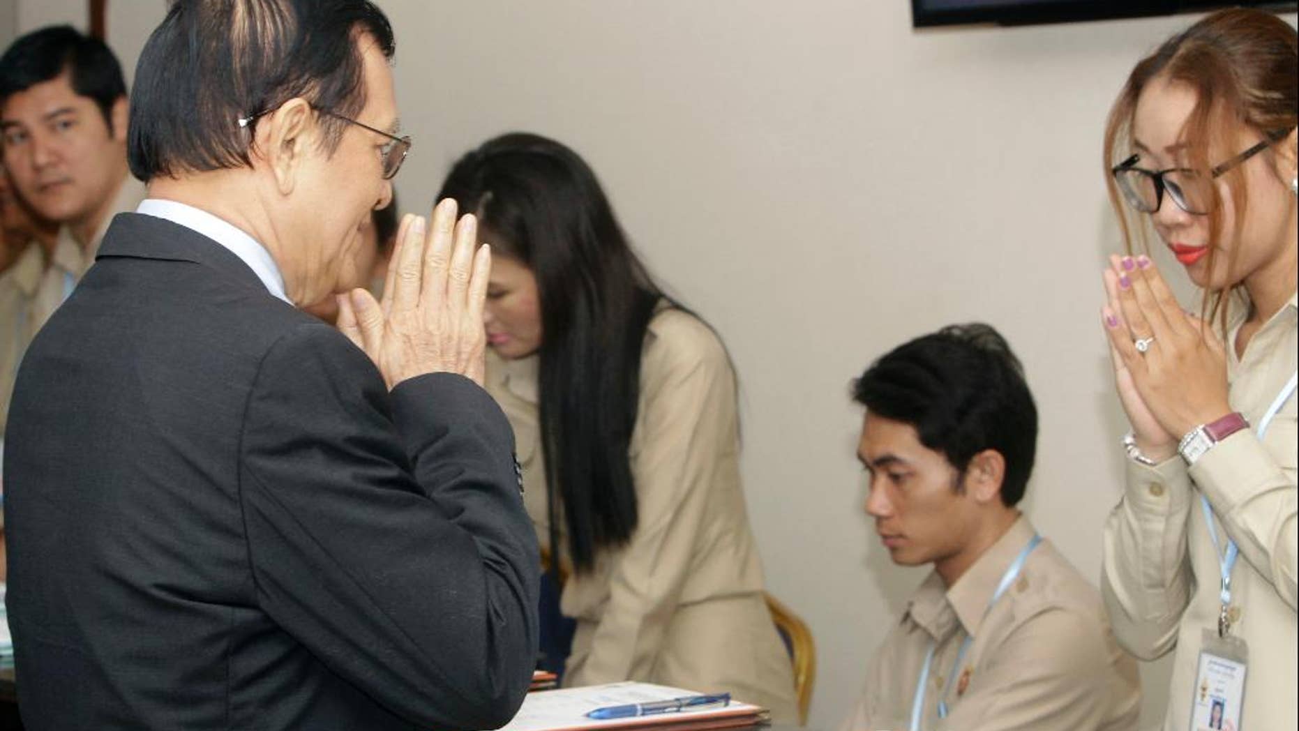 Cambodia's Rescue Party Deputy President Kem Sokha, left, greets the registrars before a meeting at National Assembly in Phnom Penh, Cambodia, Wednesday, Dec. 7, 2016. Cambodia's newly pardoned Kem Sokha has returned to parliament with a claim that he and Prime Minister Hun Sen have agreed to help reconcile their contending parties for the sake of benefiting the country. (AP Photo/Heng Sinith)