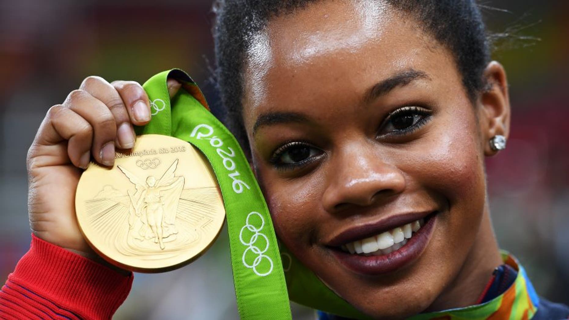 RIO DE JANEIRO, BRAZIL - AUGUST 09: Gabrielle Douglas of the United States poses for photographs with her gold medal after the medal ceremony for the Artistic Gymnastics Women's Team on Day 4 of the Rio 2016 Olympic Games at the Rio Olympic Arena on August 9, 2016 in Rio de Janeiro, Brazil. (Photo by Laurence Griffiths/Getty Images)
