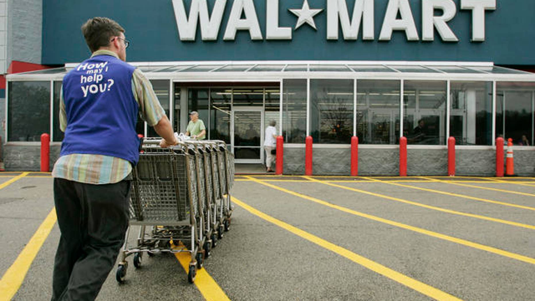 A Wal-Mart employee pushes a line of shopping carts toward the entrance of a store, in Walpole, Mass.