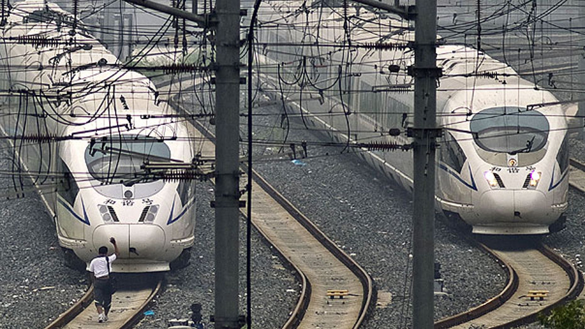 August 12: A train technician waves as he approaches CRH high-speed trains stopped on tracks at Beijing South Station in Beijing.