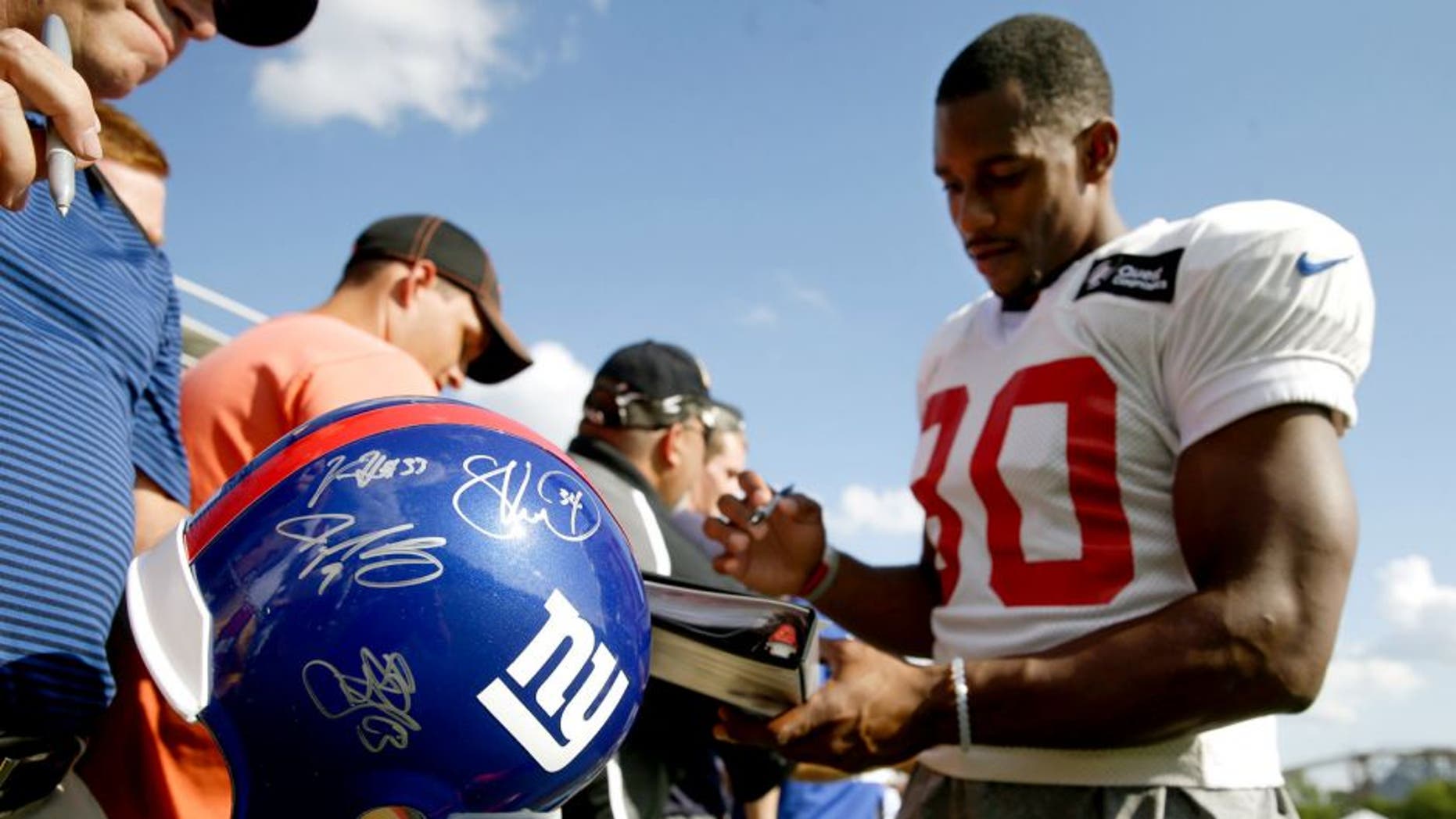 New York Giants wide receiver Victor Cruz, right, signs autographs after the Giants' joint NFL football training camp with the Cincinnati Bengals, Tuesday, Aug. 11, 2015, in Cincinnati. (AP Photo/John Minchillo)