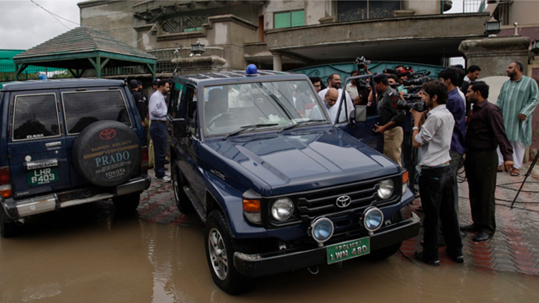 Aug. 13: Pakistani media follow a senior police officer at outside the house of an abducted American citizen in Lahore, Pakistan.
