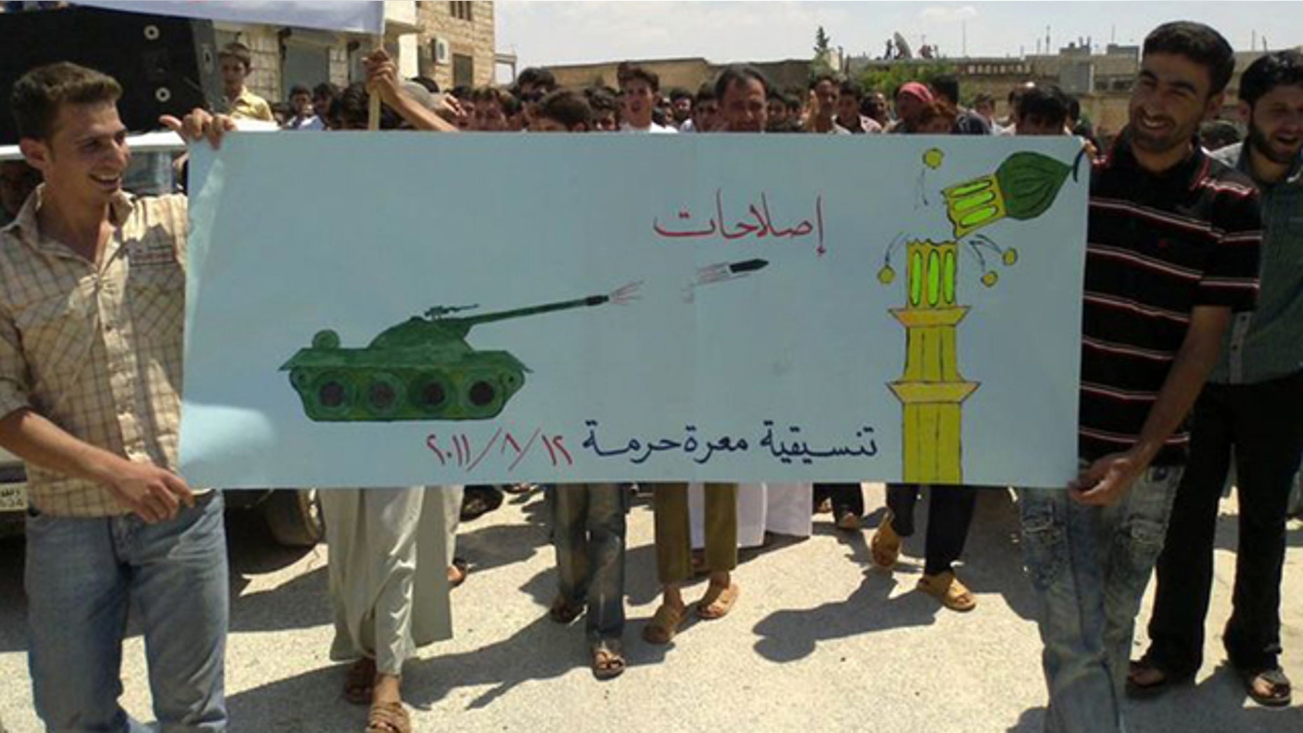 Aug. 12: In this citizen journalism image made on a mobile phone and provided by Shaam News Network, anti-Syrian President Bashar Assad protesters hold up a banner depicting a Syrian tank shelling a mosque during a demonstration against the Syrian regime, at Maarat Harma village, in Edlib province, northen Syria.