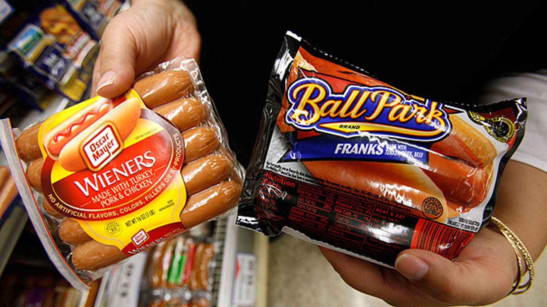 In this May 22, 2009 file photo, a store employee holds packages Oscar Meyer wieners, a Kraft product, left, and Ball Park franks, a Sara Lee Corp. product, at a local Dahl's grocery store in Des Moines, Iowa.