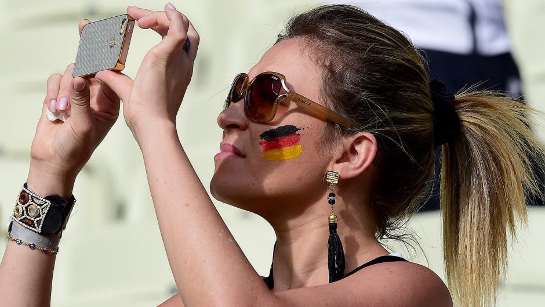 A German fan takes pictures with her phone before the start of the Group G football match between Germany and Ghana at the Castelao Stadium in Fortaleza during the 2014 FIFA World Cup on June 21, 2014. AFP PHOTO / JAVIER SORIANO