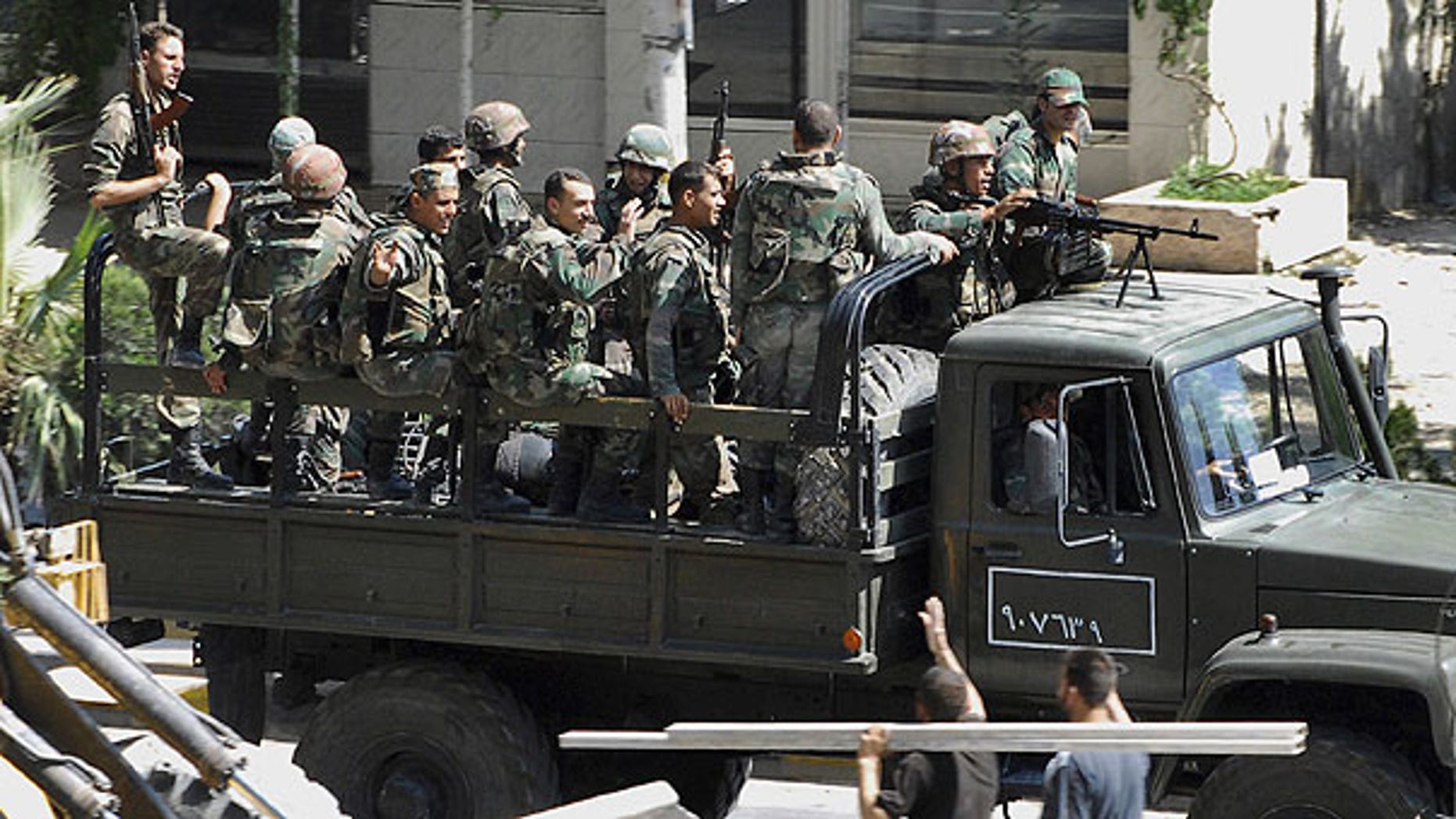Aug. 14: In this citizen journalism image, Syrian citizens, below right, wave to Syrian troops who withdraw from the Damascus suburb of Saqba, Syria, following a campaign of raids and arrests that started overnight and continued Sunday morning.