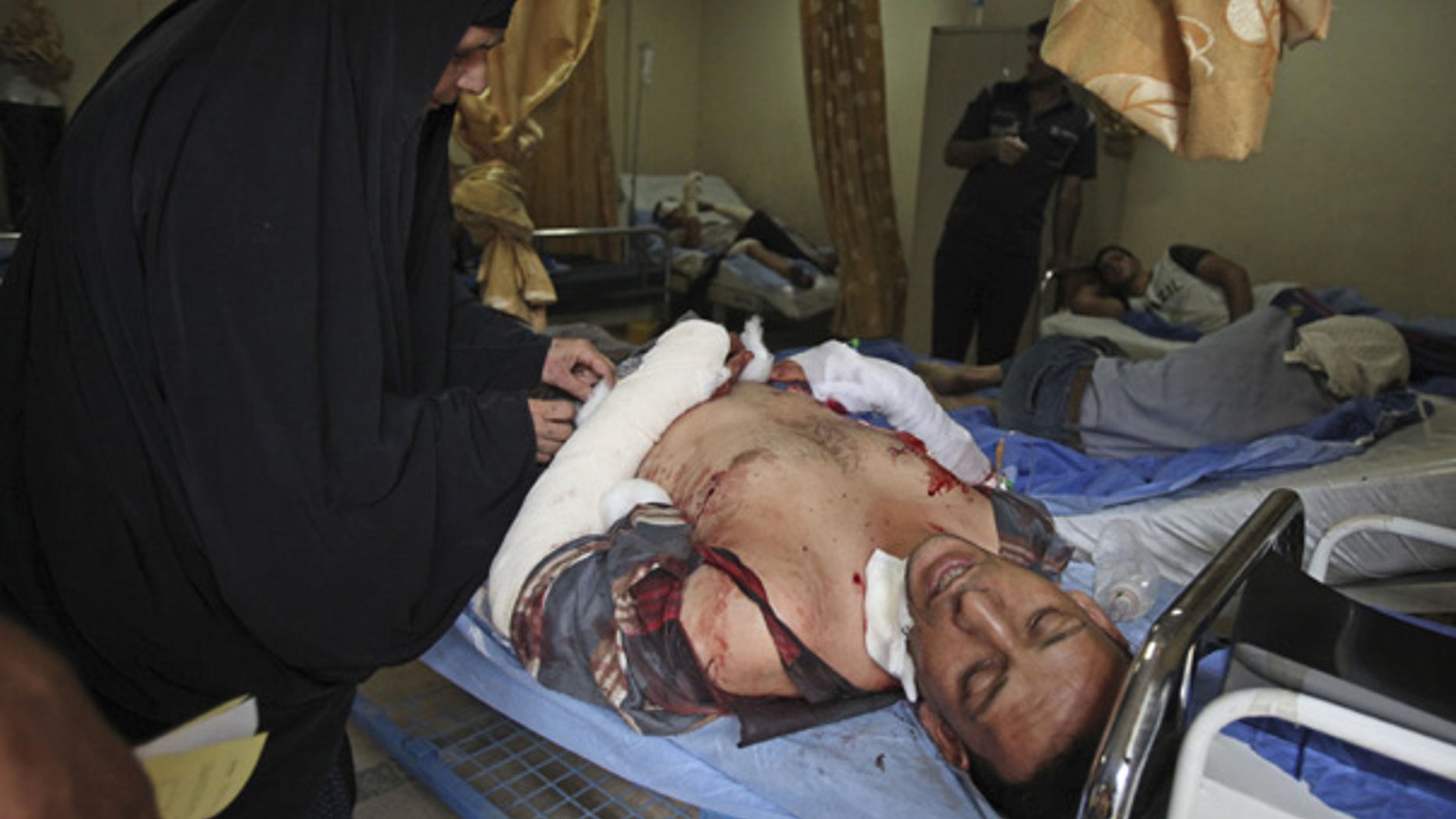 Aug. 17: An injured man is comforted by his mother at a hospital in Baghdad following a deadly homicide blast.