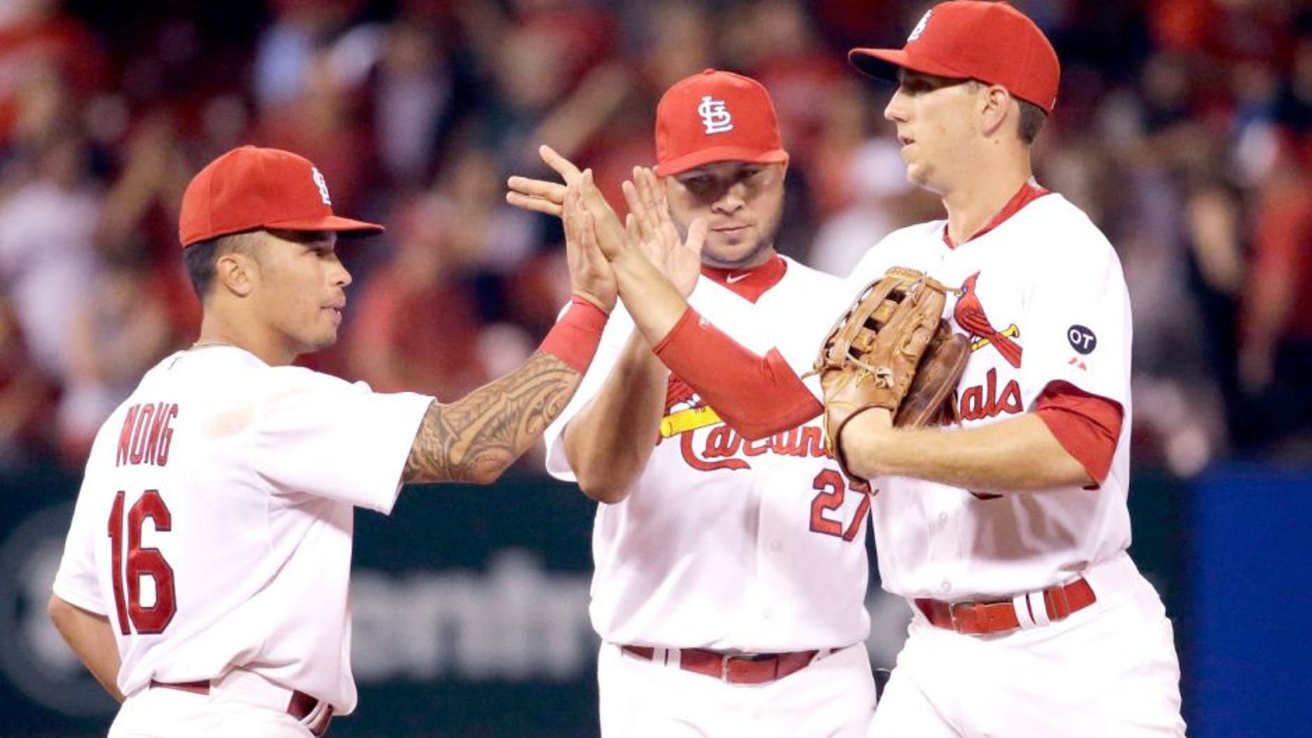 St. Louis Cardinals, from left to right, Kolten Wong, Jhonny Peralta and Stephen Piscotty celebrate following the Cardinals' 2-1 victory over the San Francisco Giants in a baseball game Monday, Aug. 17, 2015, in St. Louis. (AP Photo/Jeff Roberson)