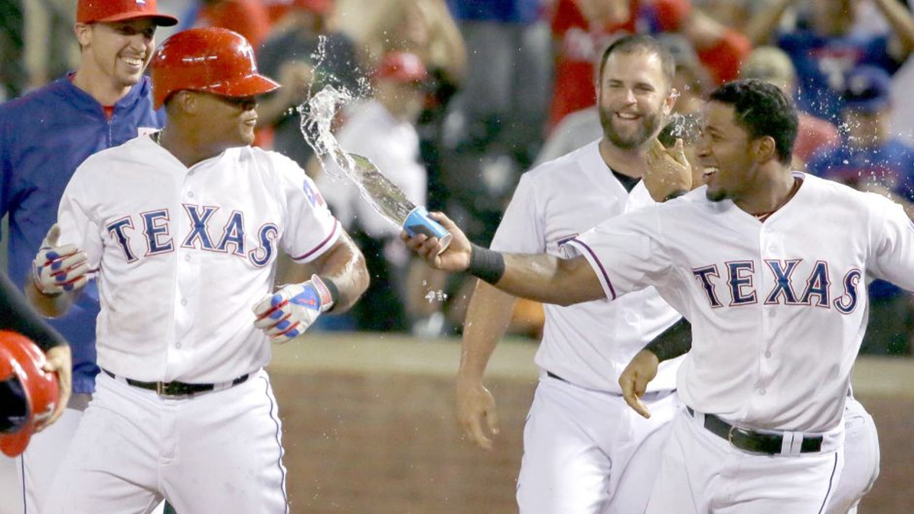 Texas Rangers Elvis Andrus, right, tosses water at teammate Adrian Beltre to celebrates Betran's bases loaded walk during the ninth inning of a baseball game against the Seattle Mariners in Arlington, Texas, Monday, Aug. 17, 2015. Rangers Ryan Strausborger scored on the play giving the Rangers the 4-3 win. (AP Photo/LM Otero)