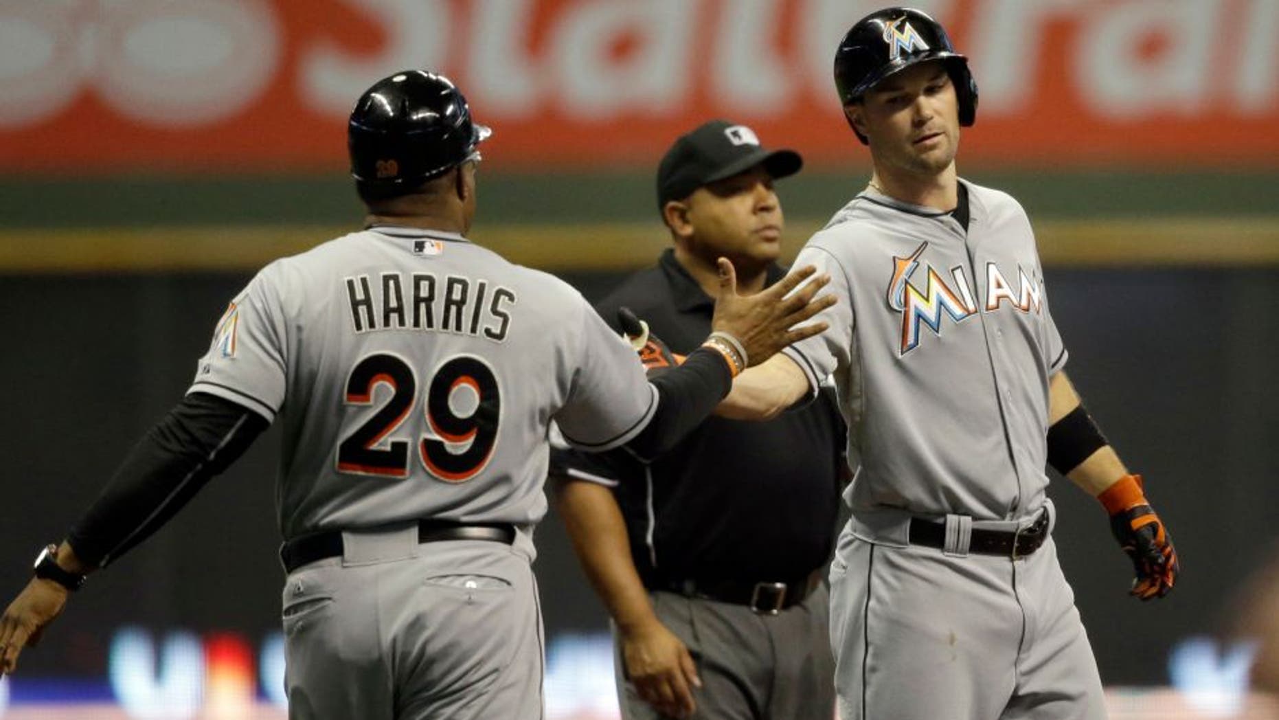 Miami Marlins' Cole Gillespie, right, is congratulated by third base coach Lenny Harris after Gillespie's three- run triple against the Milwaukee Brewers during the first inning of a baseball game, Tuesday, Aug. 18, 2015, in Milwaukee. (AP Photo/Jeffrey Phelps)