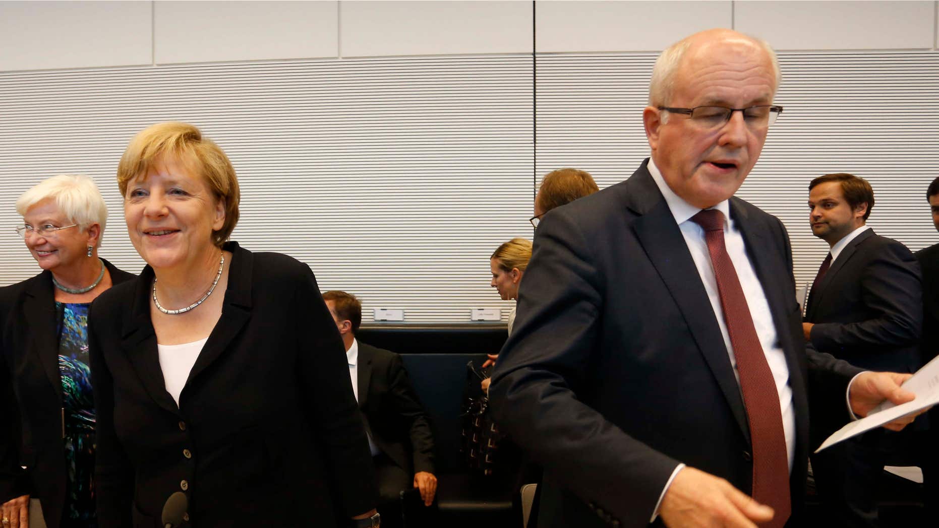 Aug. 18, 2015: German Chancellor Angela Merkel, left, smiles as parliamentary faction leader Volker Kauder opens a meeting of the Christian Democratic Party's parliamentary faction on the eve of Wednesday's vote on another bailout package for Greece, in the German Bundestag in Berlin.