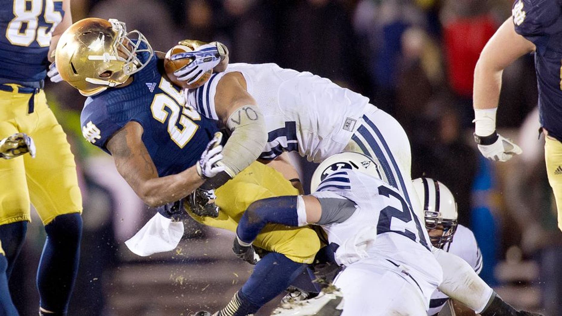 Nov 23, 2013; South Bend, IN, USA; Notre Dame Fighting Irish running back Tarean Folston (25) is tackled by BYU Cougars linebacker Uani 'Unga (41) and safety Craig Bills (20) in the third quarter at Notre Dame Stadium. Notre Dame won 23-13. Mandatory Credit: Matt Cashore-USA TODAY Sports