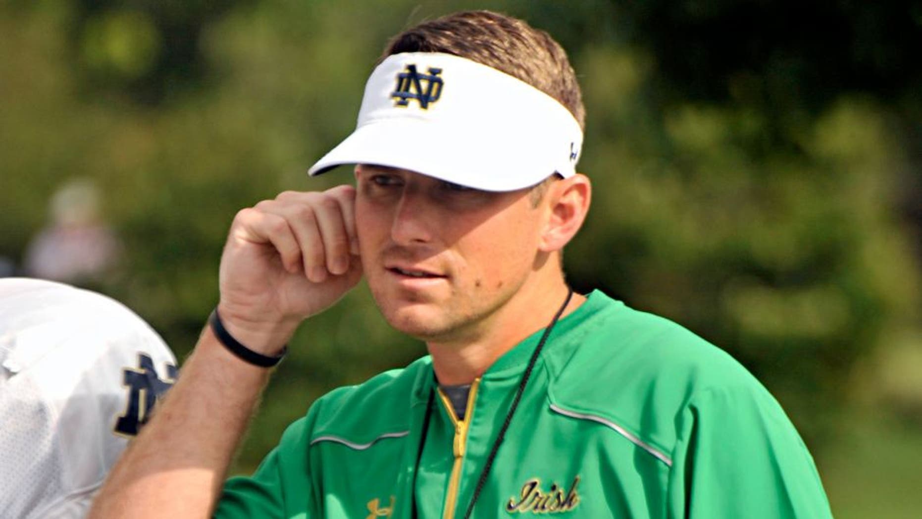 In this Saturday, Aug. 15, 2015, photo, Notre Dame offensive coordinator Mike Sanford walks onto the practice field during an NCAA college football practice in South Bend, Ind. Sanford is Notre Dame's new offensive coordinator but what exactly does that mean for the promising 33-year-old assistant. Fighting Irish coach Brian Kelly has always had an hands on approach with his offense and quarterbacks, and two of Kelly's former offensive coordinators are still on staff. (AP Photo/Joe Raymond)