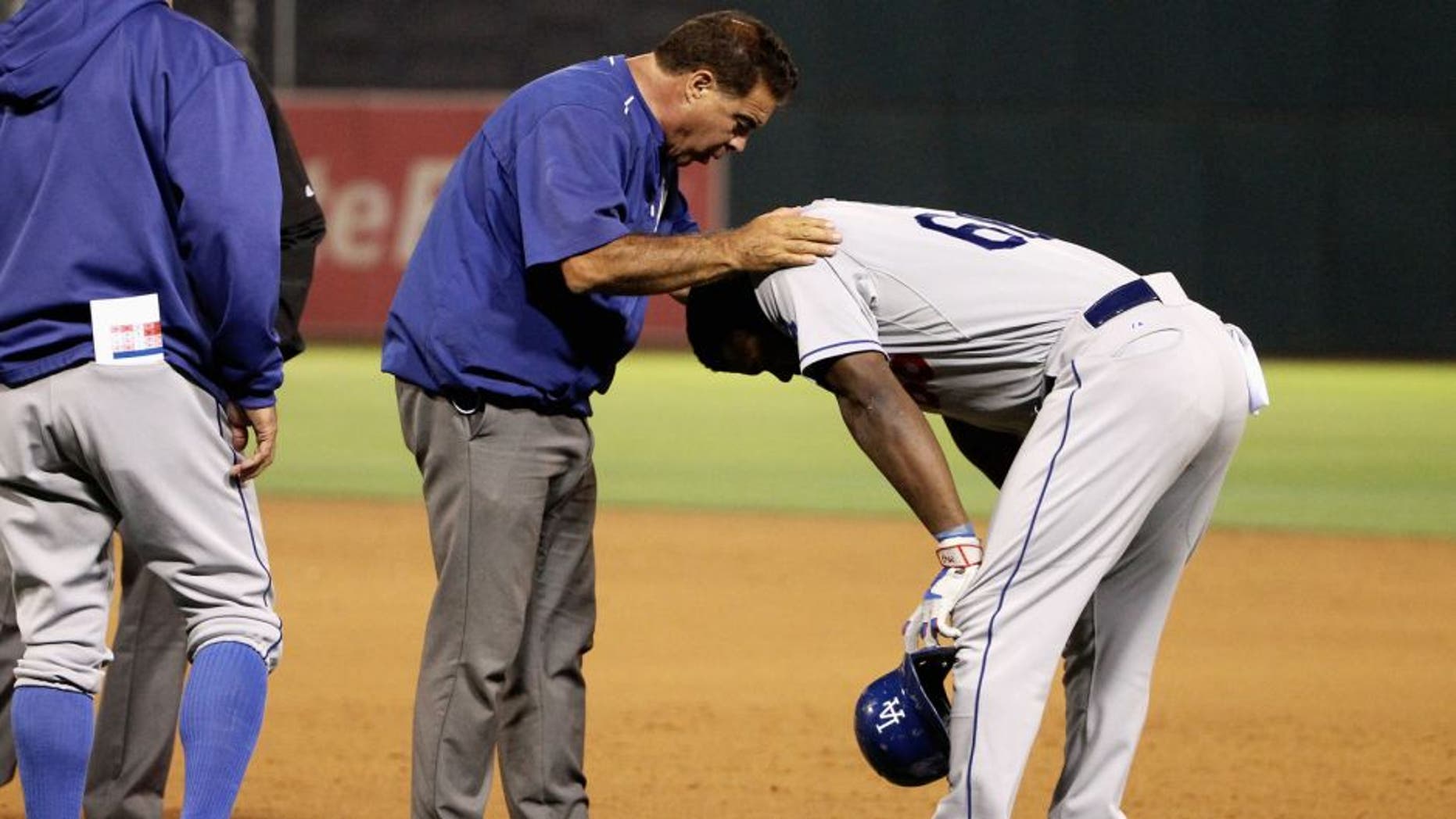 OAKLAND, CA - AUGUST 18: Yasiel Puig #66 of the Los Angeles Dodgers is looked at by a trainer in the eighth inning of their game against the Oakland Athletics at O.co Coliseum on August 18, 2015 in Oakland, California. Puig left the game after the play. (Photo by Ezra Shaw/Getty Images)