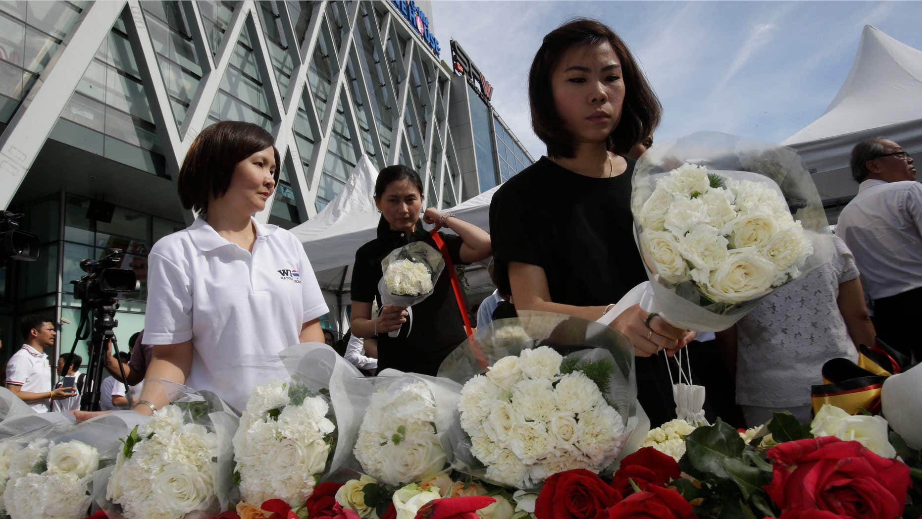 Aug. 21, 2015: People leave flowers at a shopping plaza across from the Erawan Shrine at Rajprasong intersection, the scene of Monday's bombing, for a multi-denominational religious service for victims in Bangkok, Thailand