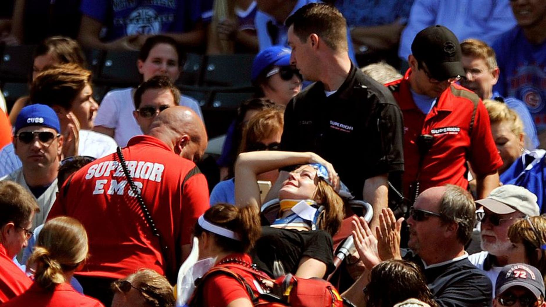 A fan is carried away after being hit a by a line-drive foul ball during the first inning of a baseball game between the Chicago Cubs and the Atlanta Braves at Wrigley Field, Sunday, Aug. 23, 2015, in Chicago. (AP Photo/Paul Beaty)