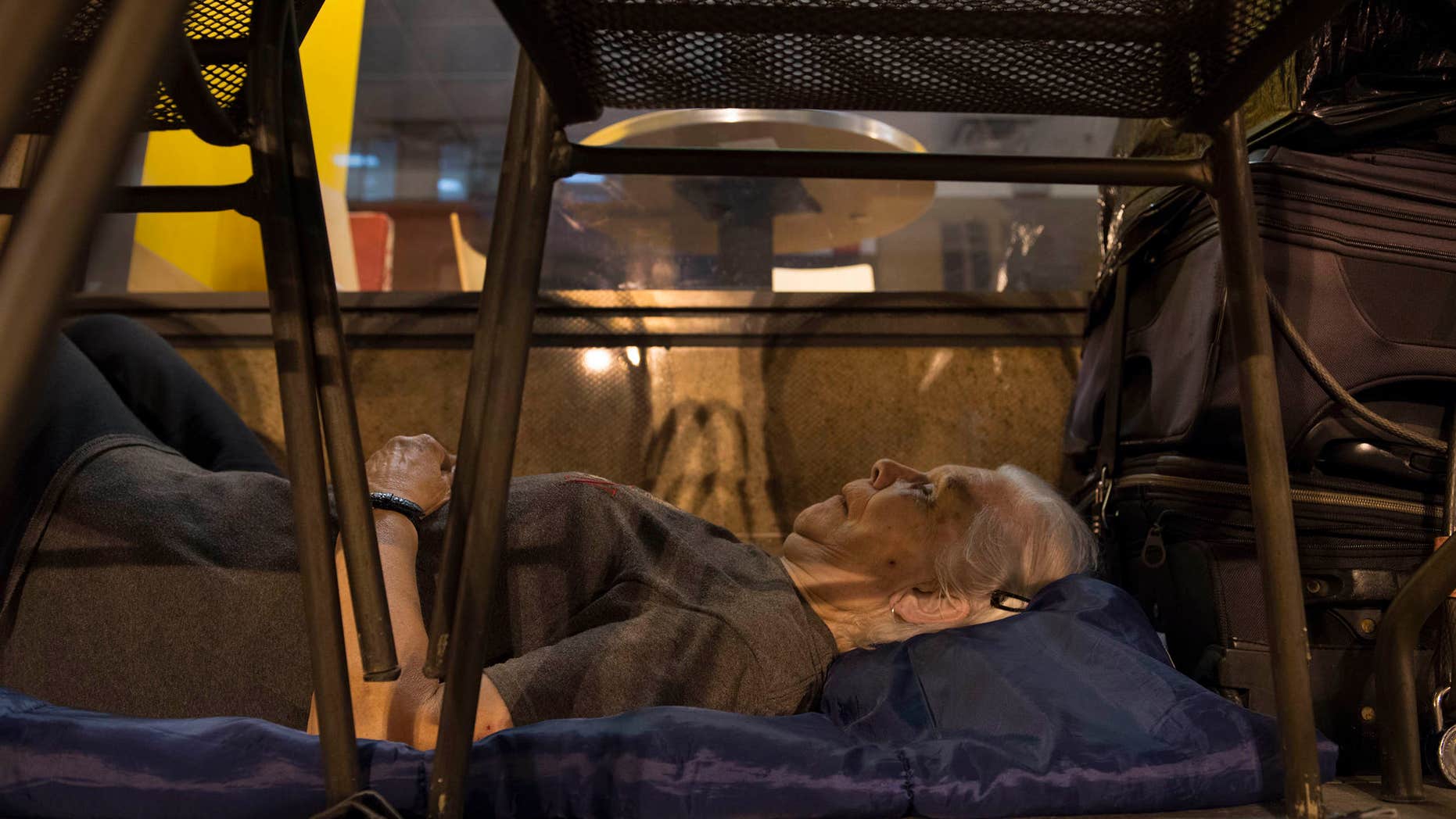 In this Aug. 10, 2016 photo, with suitcases in arms reach, homeless woman Wanda Witter beds down in her sleeping spot outside the Au Bon Pain on 13th and G Street in Washington, DC Witter, who is 80 years old, was recently attacked at the location suffering a black eye and two stitches.