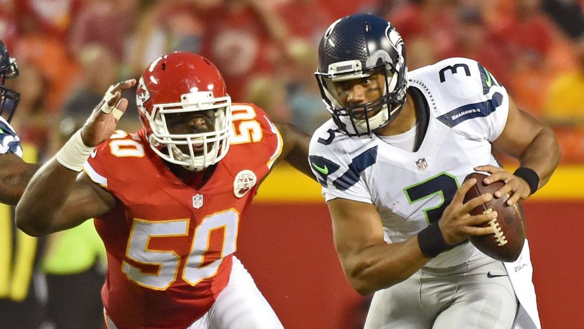 KANSAS CITY, MO - AUGUST 21: Quarterback Russell Wilson #3 of the Seattle Seahawks scrambles away from linebacker Justin Houston #50 of the Kansas City Chiefs during the first half of a preseason game at Arrowhead Stadium on August 21, 2015 in Kansas City, Missouri. (Photo by Peter G. Aiken/Getty Images)