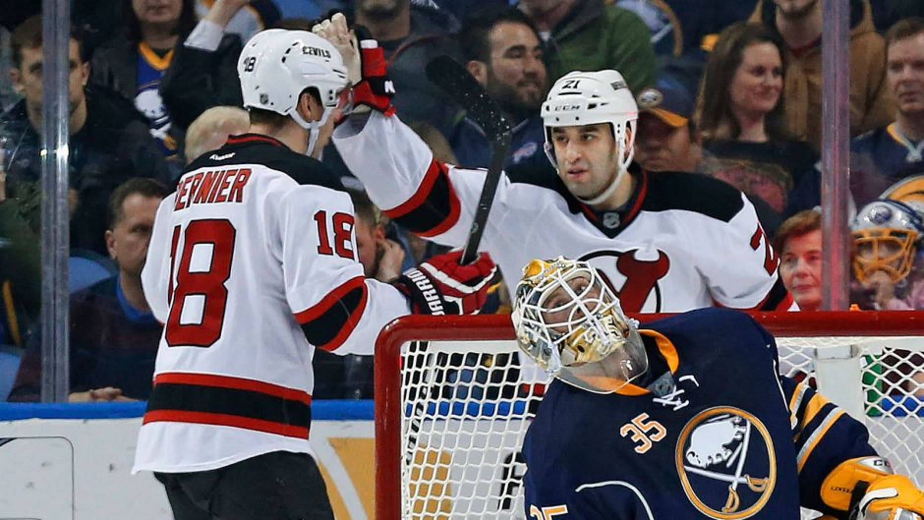 Mar 20, 2015; Buffalo, NY, USA; New Jersey Devils right wing Steve Bernier (18) celebrates with center Scott Gomez (21) after Bernier scored on Buffalo Sabres goalie Anders Lindback (35) during the second period at First Niagara Center. Mandatory Credit: Kevin Hoffman-USA TODAY Sports