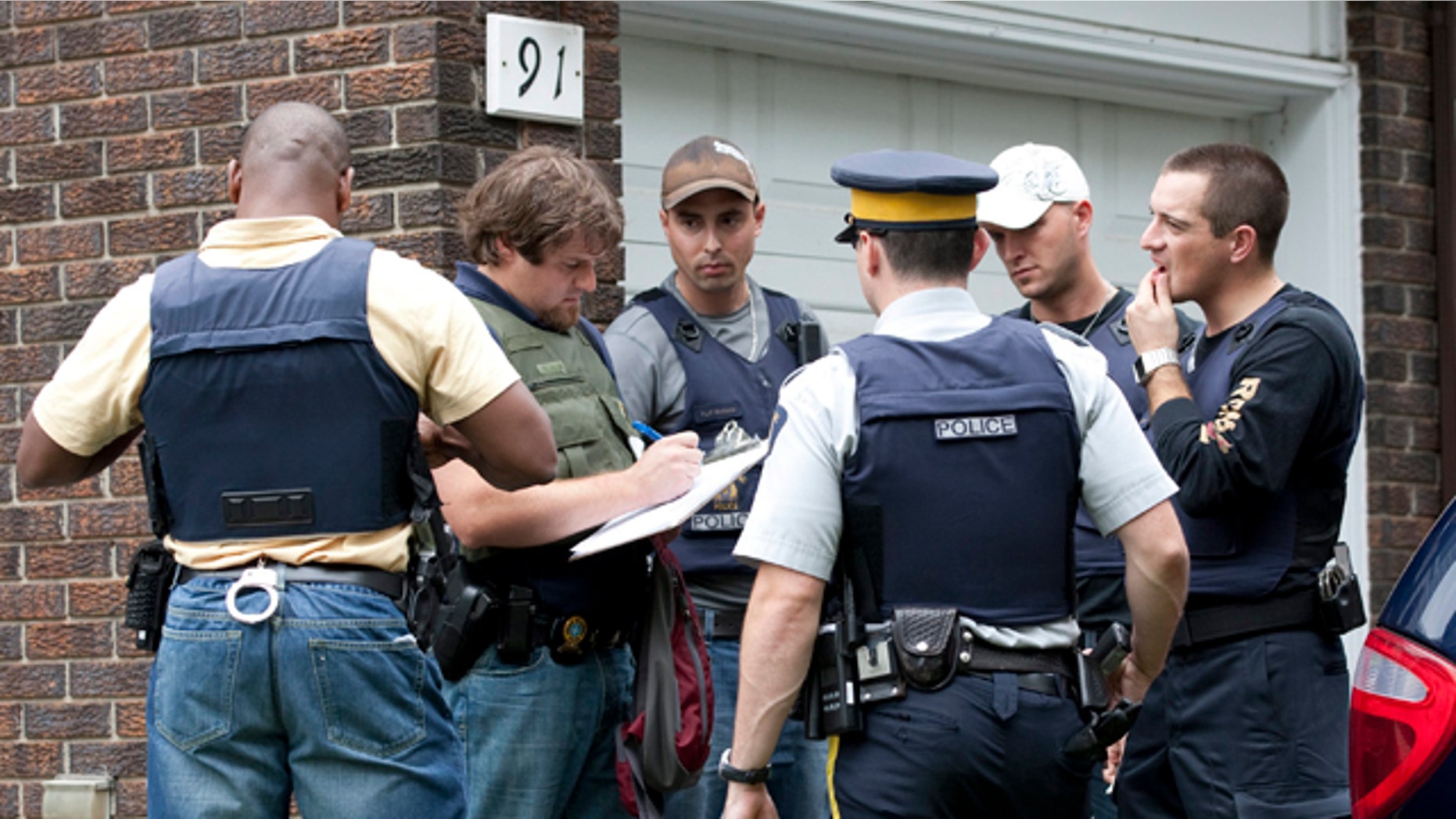 Aug. 25: Police talk outside of a home in the west end of Ottawa, Canada, after police arrested two Ottawa residents on terror-related charges.