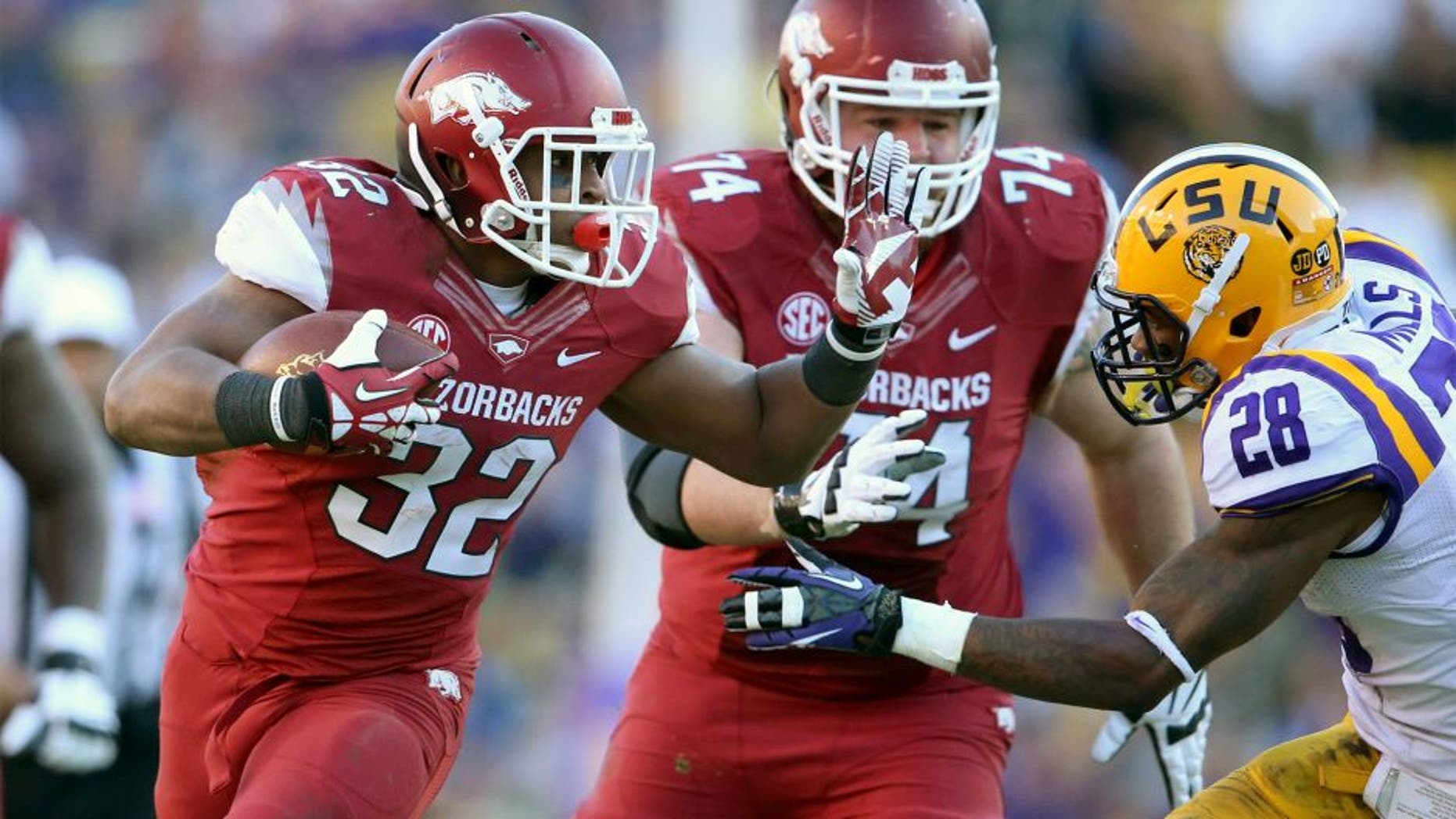 Nov 29, 2013; Baton Rouge, LA, USA; Arkansas Razorbacks running back Jonathan Williams (32) fights off LSU Tigers cornerback Jalen Mills (28) in the second half against the Arkansas Razorbacks at Tiger Stadium. LSU defeated Arkansas 31-27. Mandatory Credit: Crystal LoGiudice-USA TODAY Sports