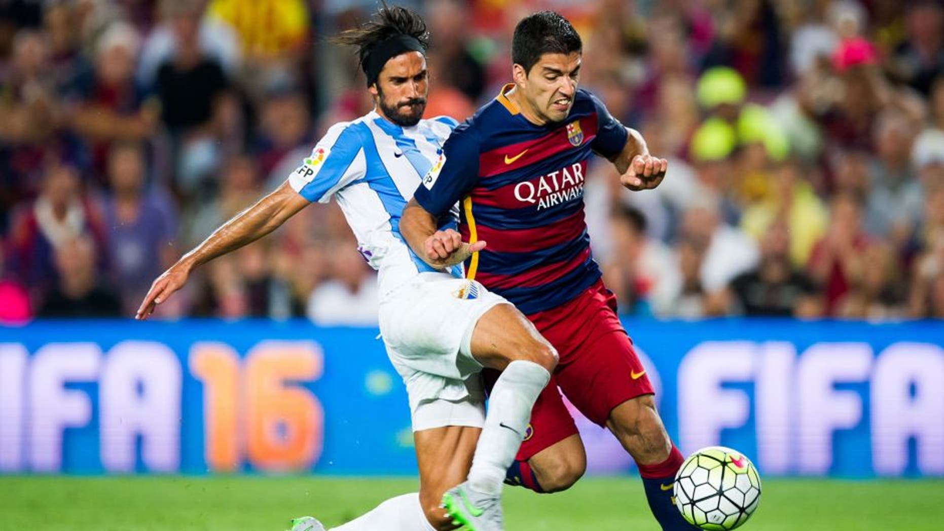 BARCELONA, SPAIN - AUGUST 29: Luis Suarez of FC Barcelona is brought down by Marcos Angeleri of Malaga CF during the La Liga match between FC Barcelona and Malaga CF at Camp Nou on August 29, 2015 in Barcelona, Spain. (Photo by Alex Caparros/Getty Images)